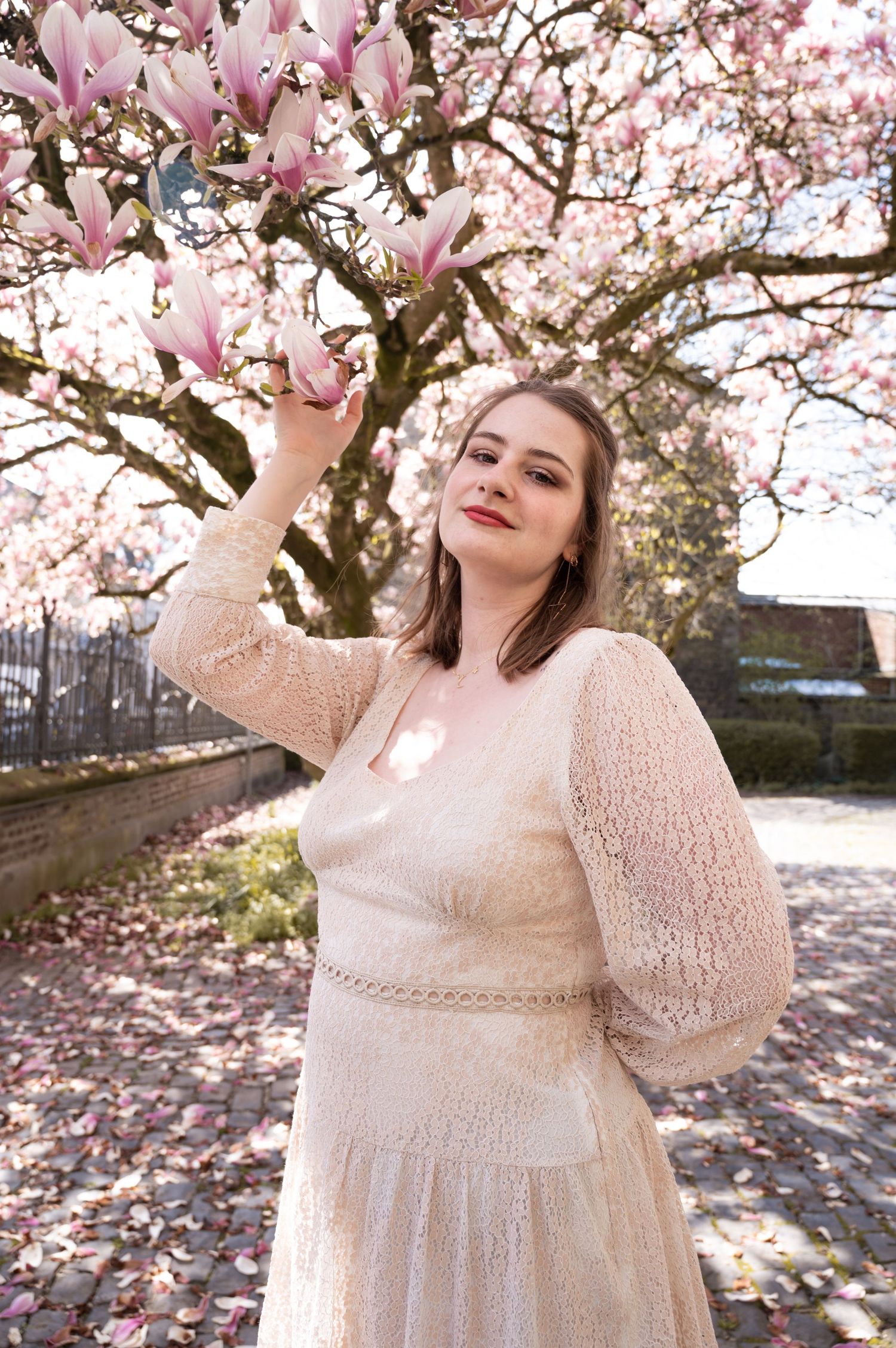 À Ciney, portrait de femme photographiée en extérieur près d’un magnolia en fleurs lors d’une séance photo printanière