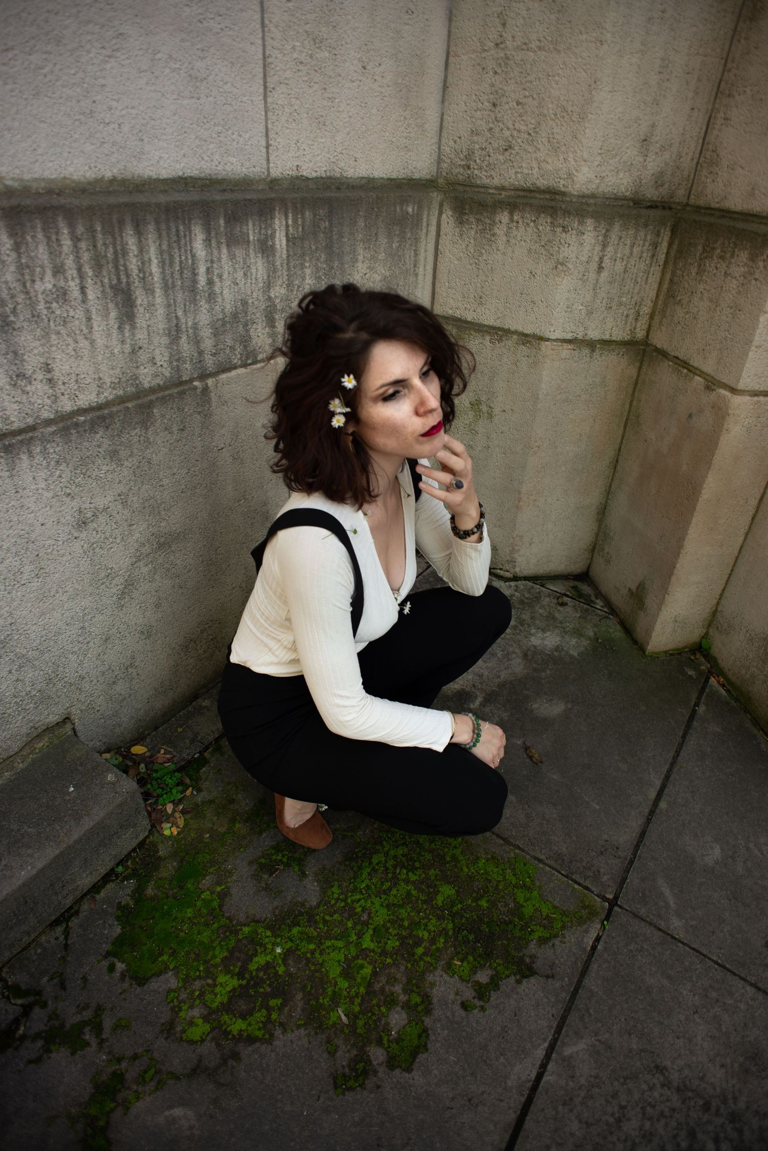À Liège, au mémorial interallié de Cointe, portrait d’une femme accroupie regardant au loin devant un mur du monument