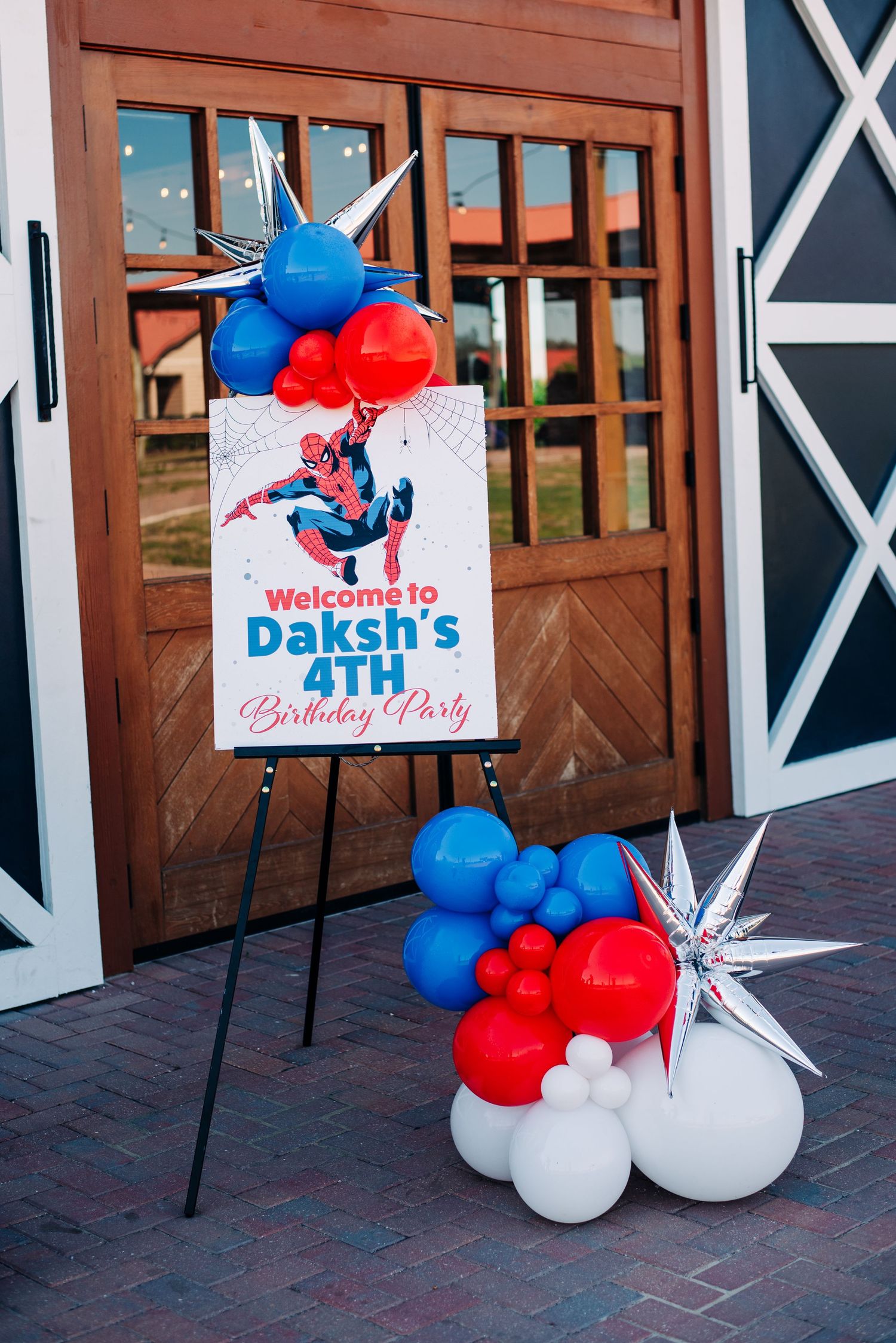 Spider-Man themed welcome sign for Daksh's 4th birthday party, decorated with red, blue, and white balloons.
