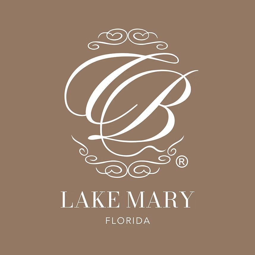 Elegant white monogram logo design for Lake Mary Florida with decorative swirls on brown background.