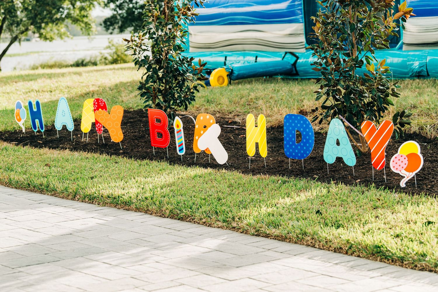 Colorful Happy Birthday yard sign letters displayed in green grass garden for outdoor birthday party celebration.