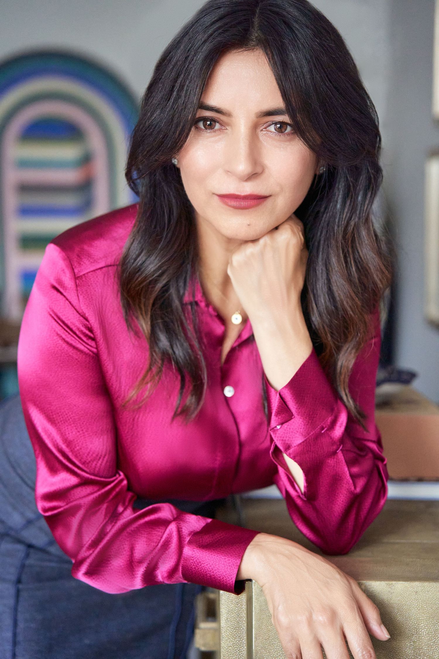 Confident brunette woman in pink satin blouse posing for professional headshot portrait.