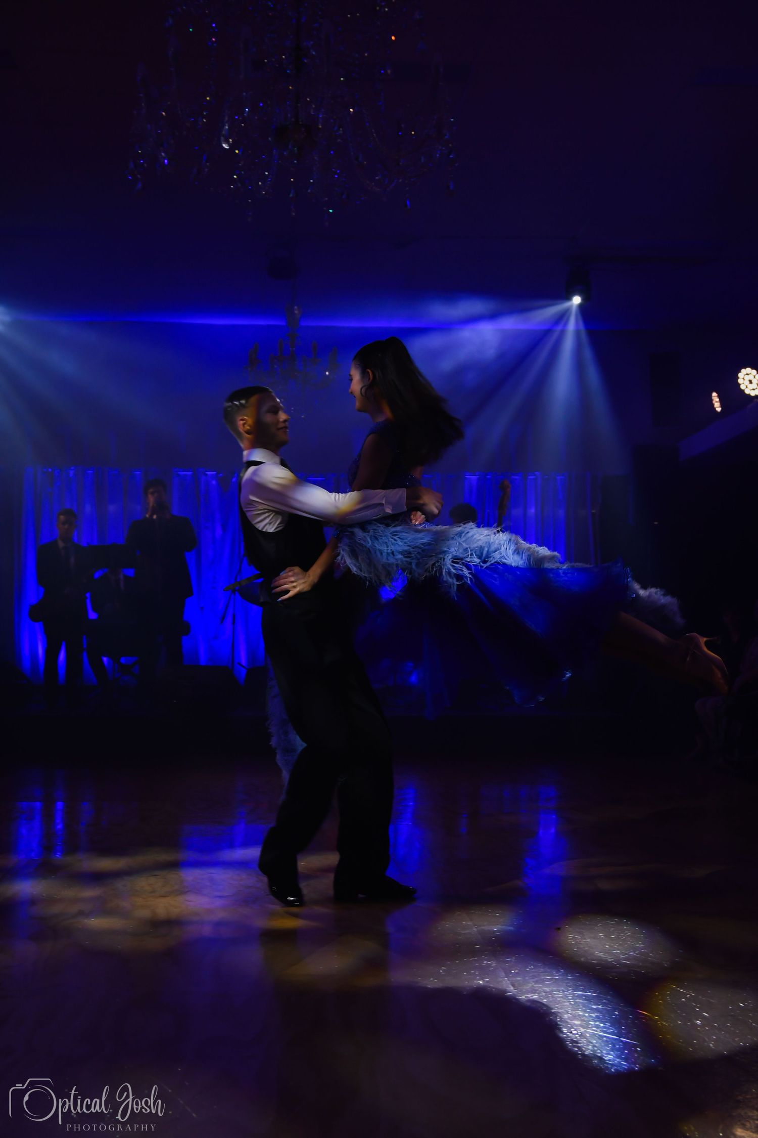 Two dancers perform a dramatic lift against deep blue stage lighting during a dance performance on a dark stage. (Optical Josh)