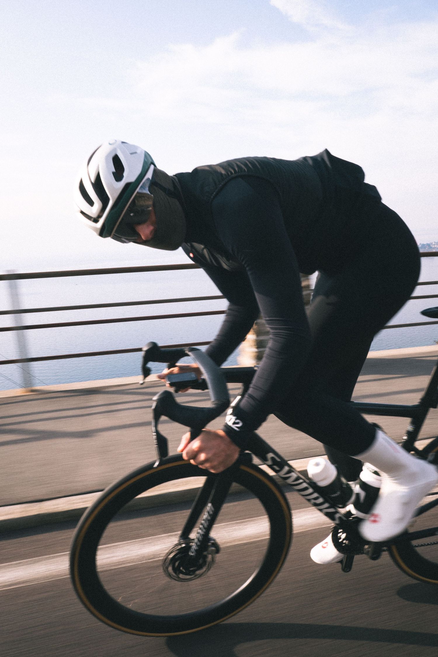 A cyclist in black riding a road bike at high speed shown in a dynamic motion sequence.