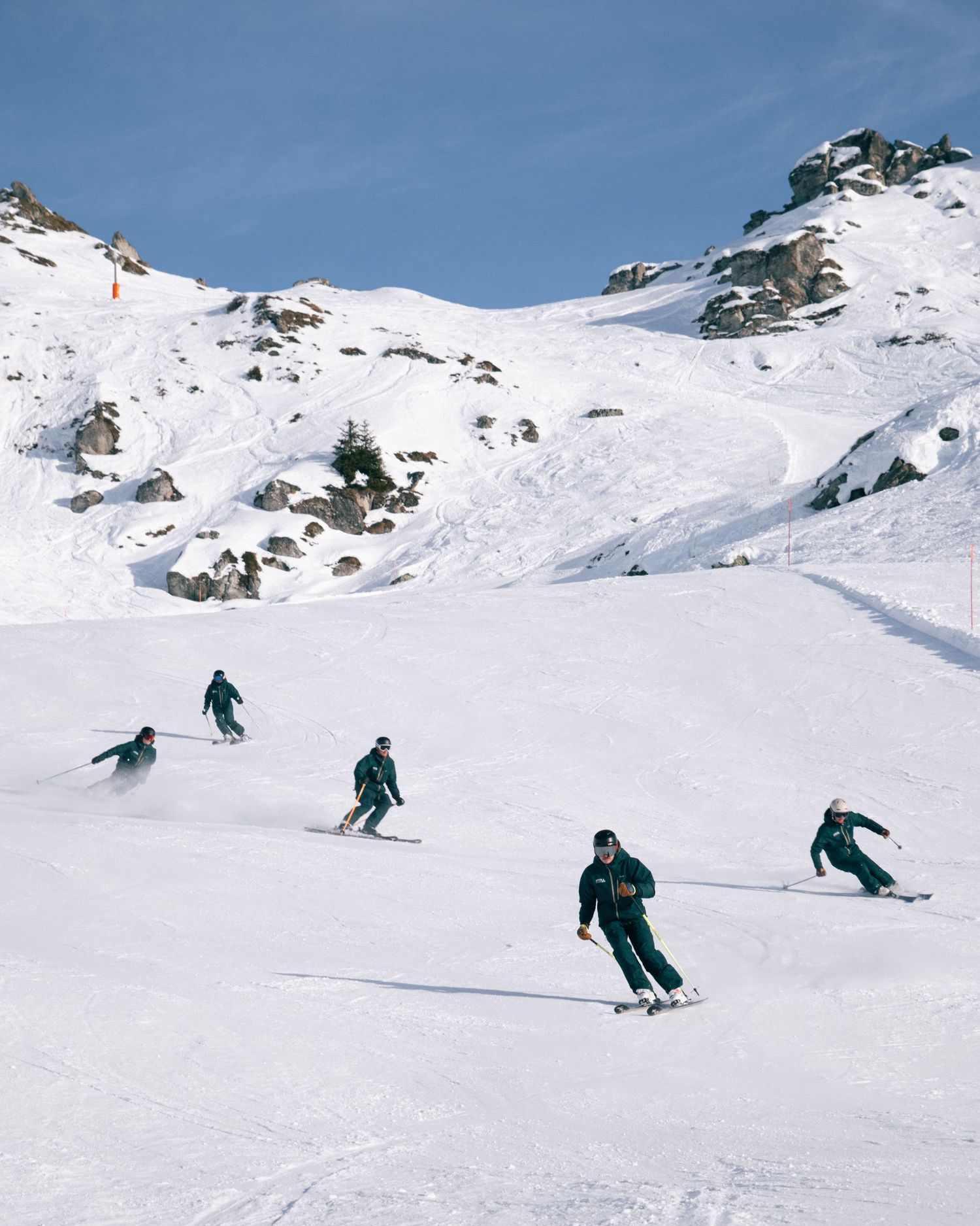A skier carves through fresh powder snow on a pristine mountain slope during a sunny winter day.