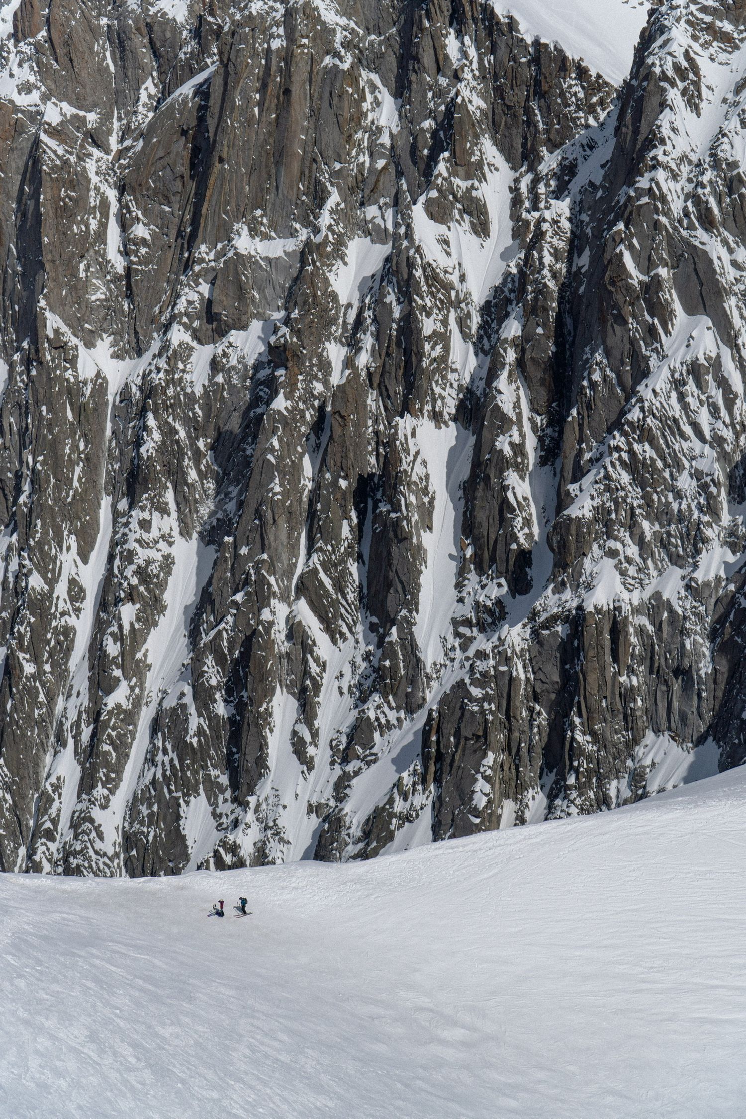 Snow-covered rocky mountain peaks with jagged cliffs and steep slopes in winter conditions.