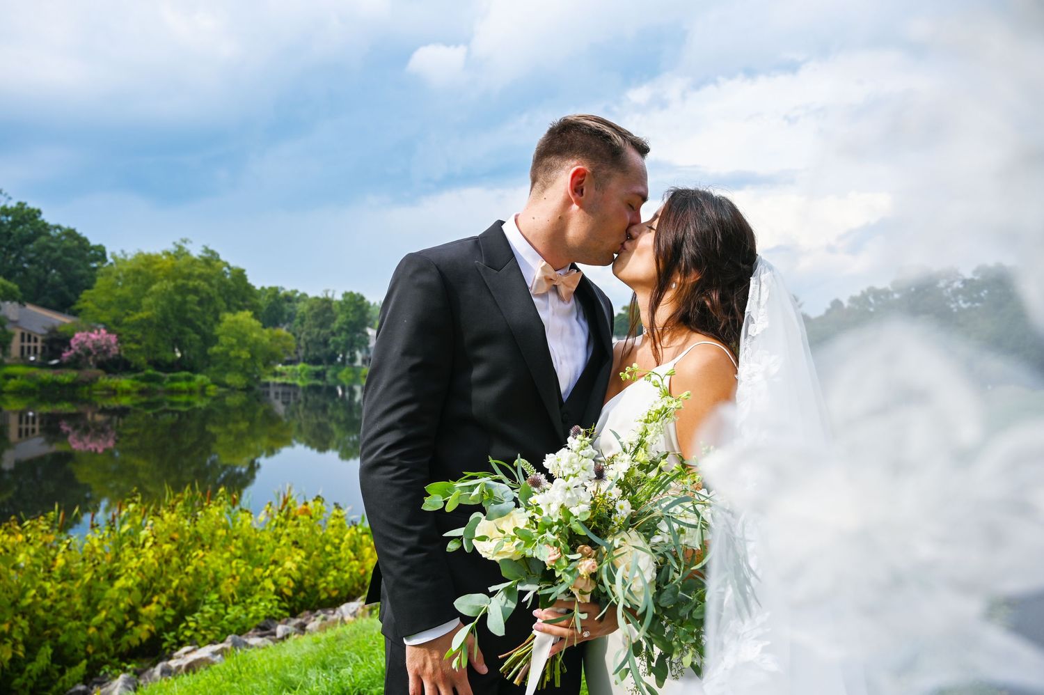 Romantic kiss with the bride’s veil flowing softly around the couple.