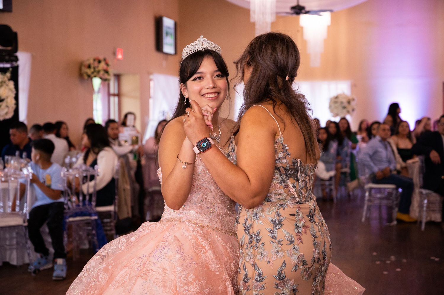 Heartwarming first dance moment with the mother smiling toward the camera.