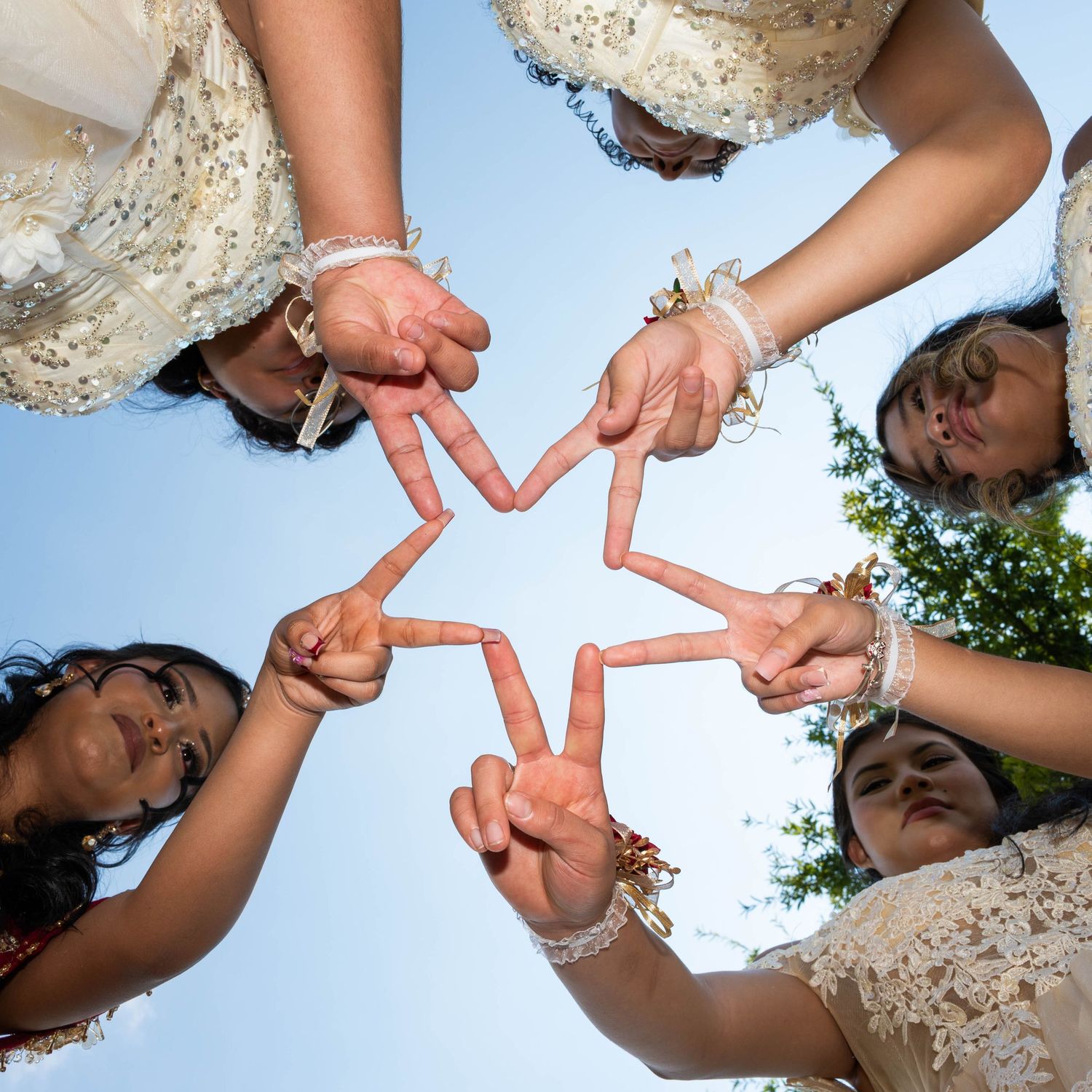 Fun photo of the quinceañera and her friends creating peace signs together in a star formation.
