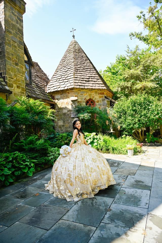 Stunning portrait showing off the grounds of The Cloisters Castle with the quinceañera looking back at the camera in her beautiful gold dres