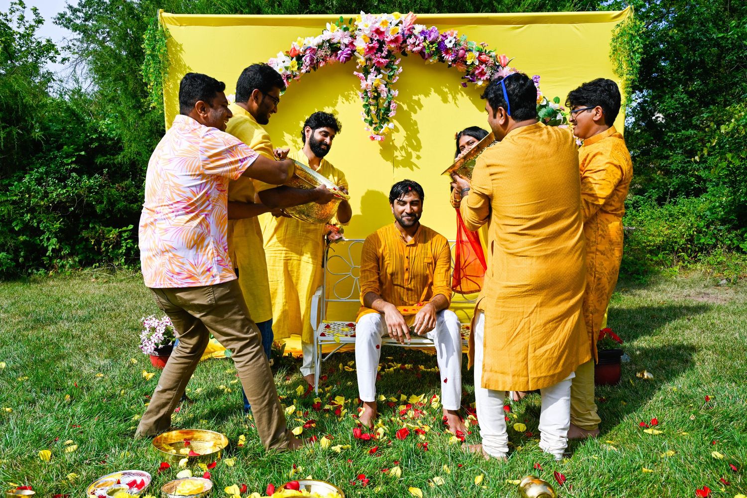 Friends playfully dumping water on the groom during the energetic haldi celebration.
