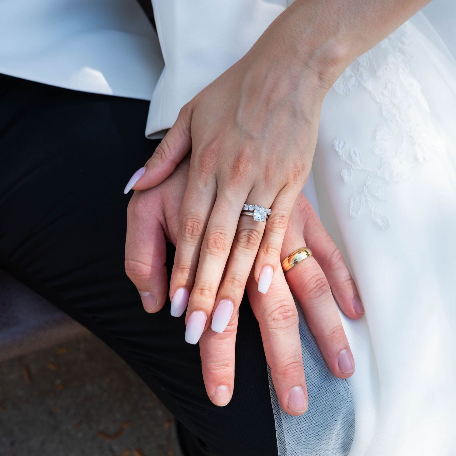 Bride and groom holding hands while showing off their wedding rings.