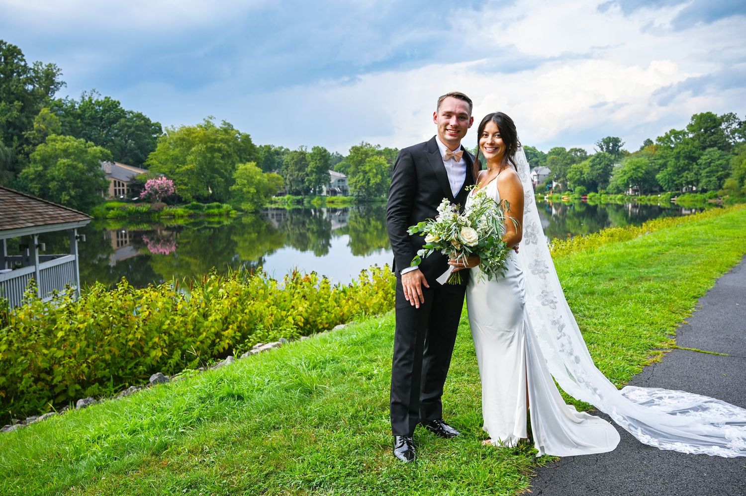 Newlyweds standing together beside the lake in a romantic portrait.