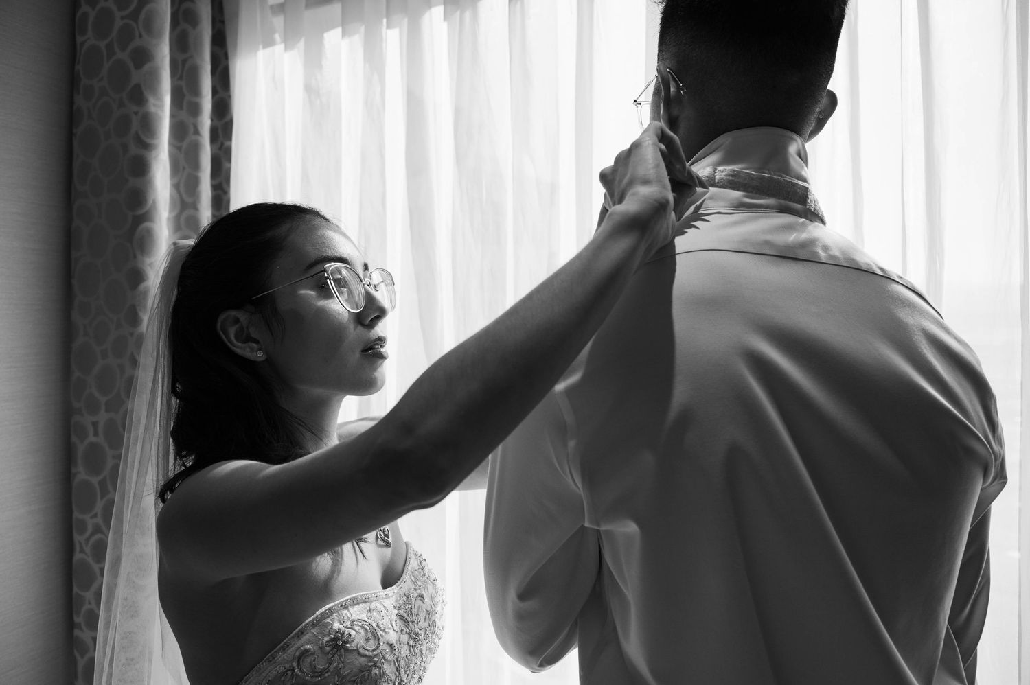 Sweet moment of the bride helping the groom get ready before the ceremony.