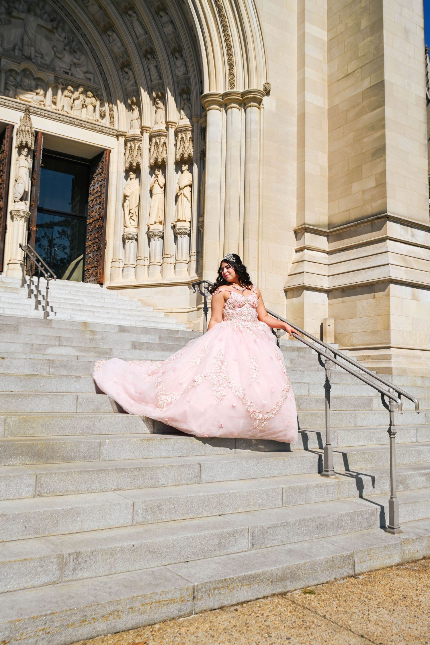 Quinceañera gracefully walking down the steps of the Washington National Cathedral.