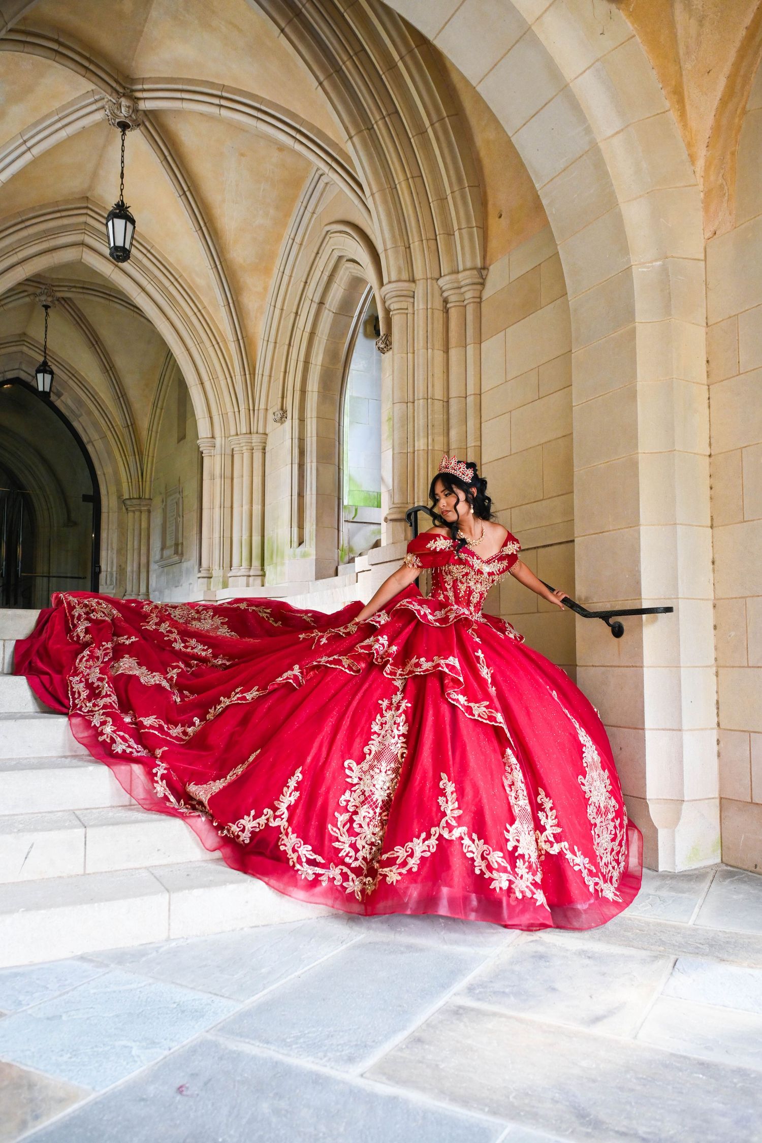 Quinceañera gracefully walking down the cathedral stairs in her stunning red gown.