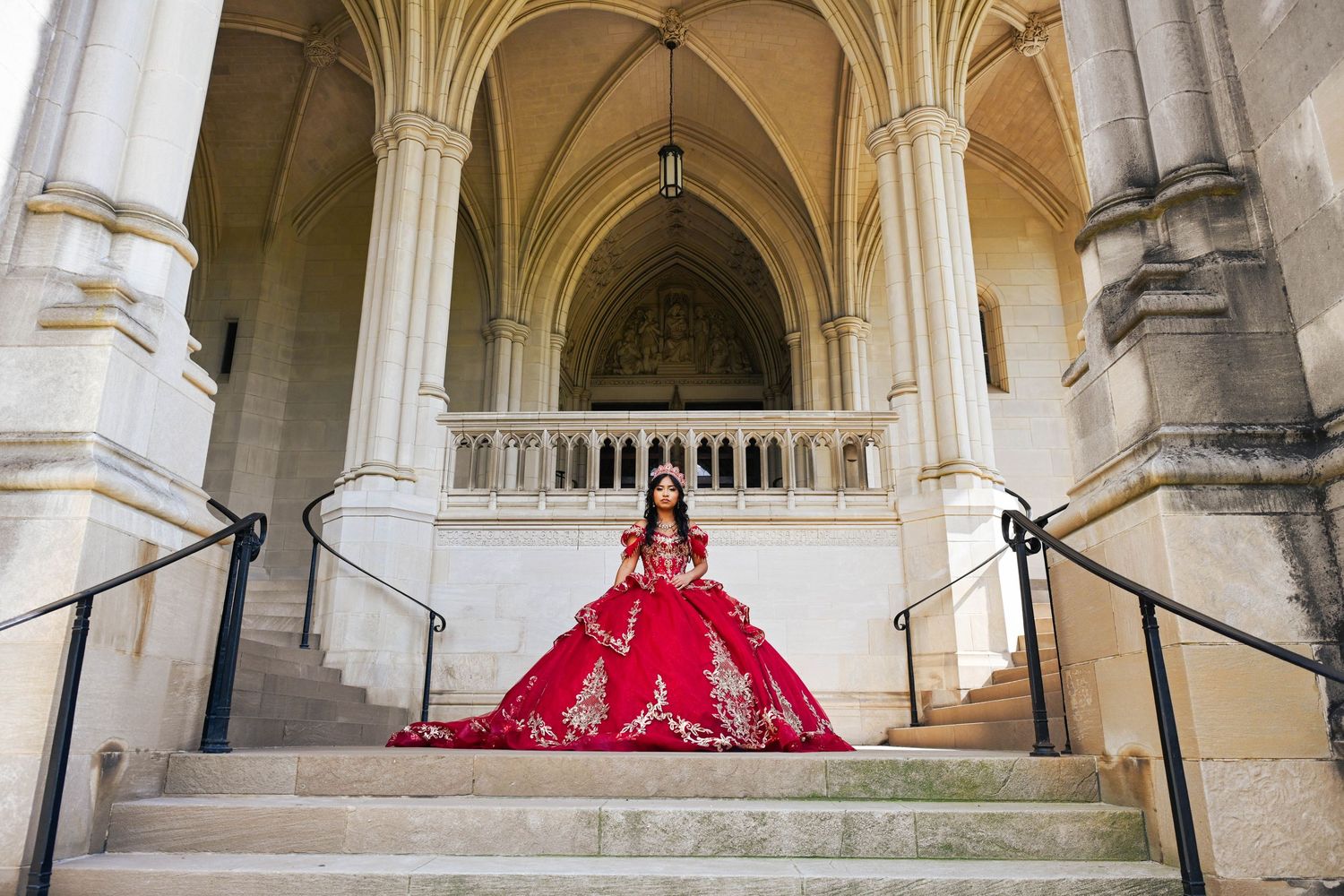 Beautiful portrait of the quinceañera standing at the top of the stairs surrounded by breathtaking architecture.