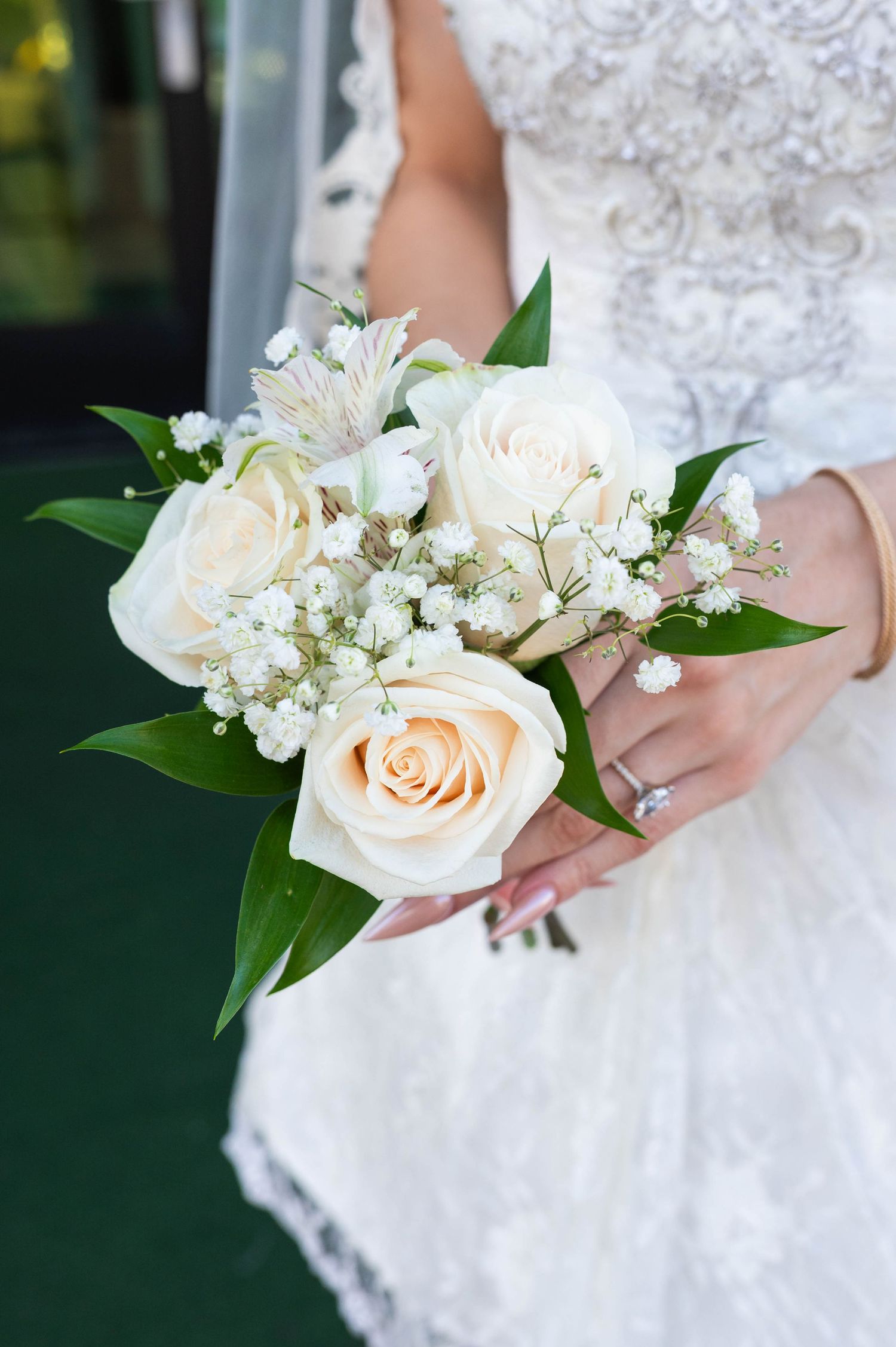 Bride proudly showing off her wedding bouquet filled with beautiful floral details.