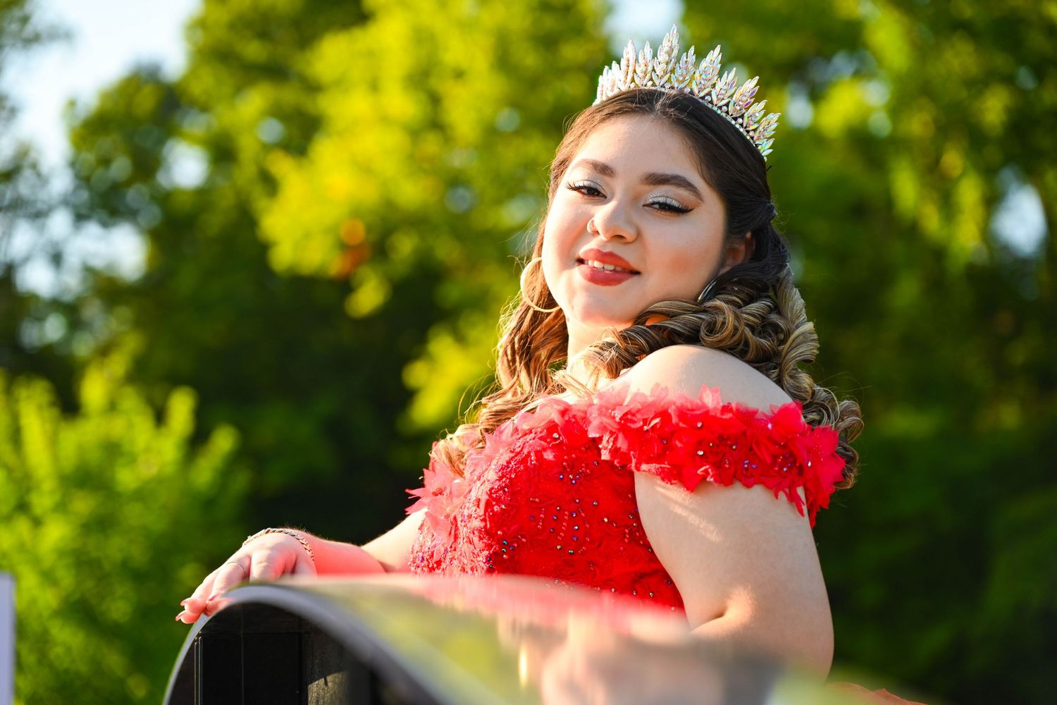 Quinceañera smiling brightly toward the camera during her portrait session.