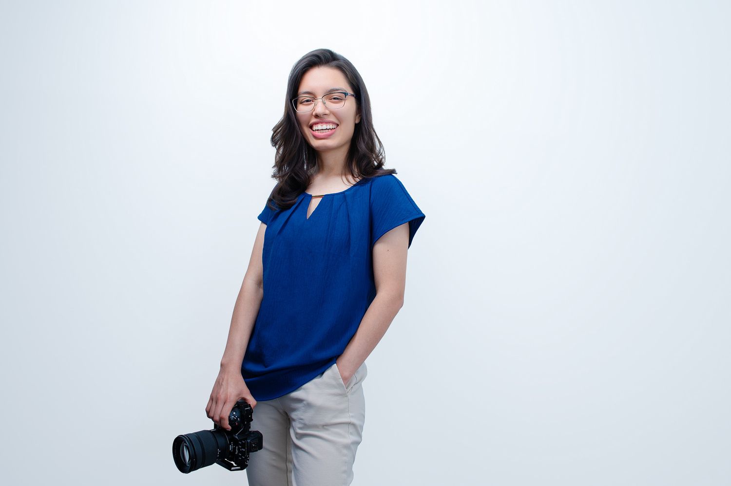 Carefree portrait of the photographer smiling at the camera with a camera in hand. Rivera's Photography