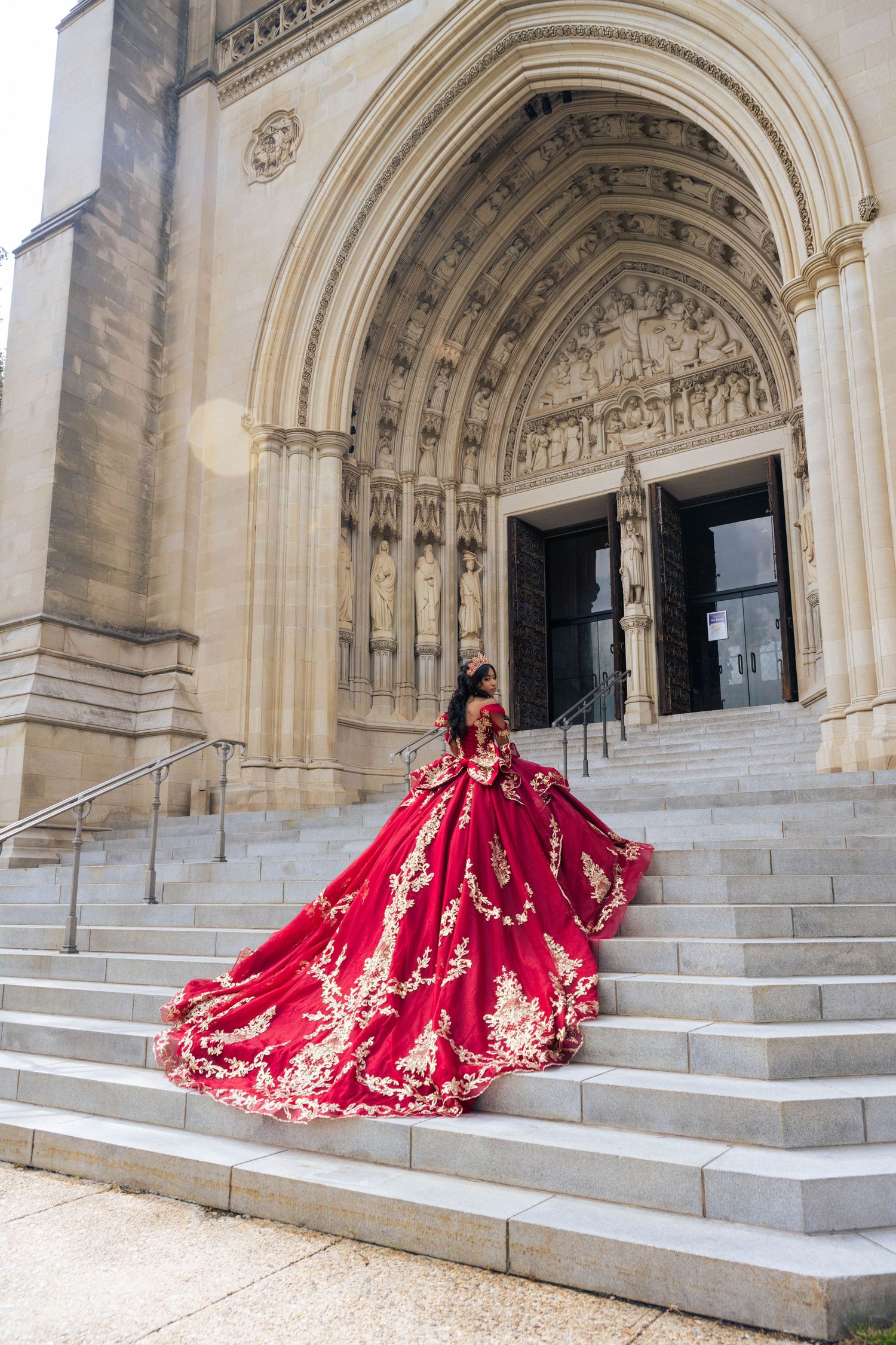 Quinceañera walking up the stairs while showing off the long flowing train of her dress.