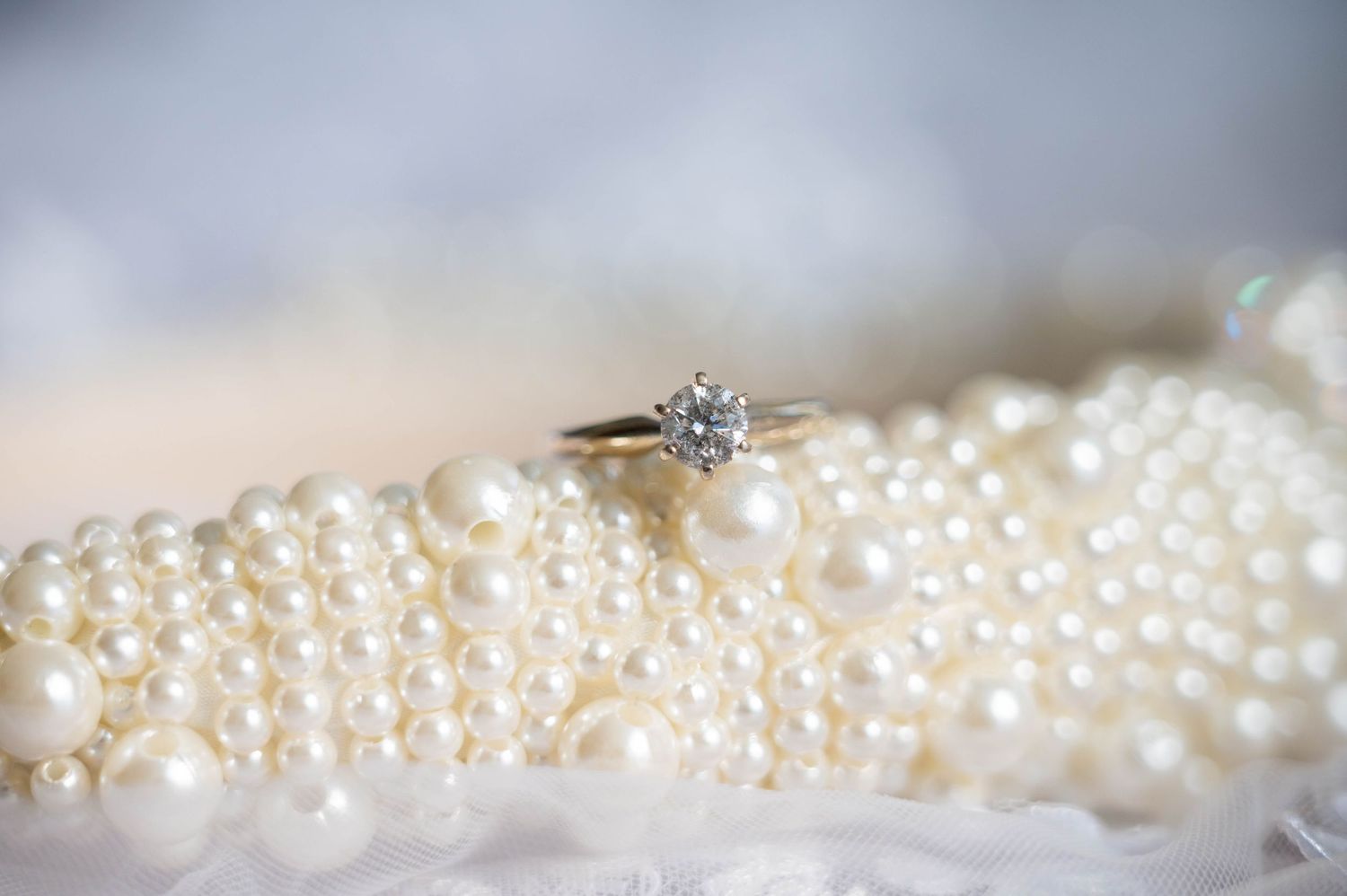 Elegant detail shot of the wedding ring placed on pearls.