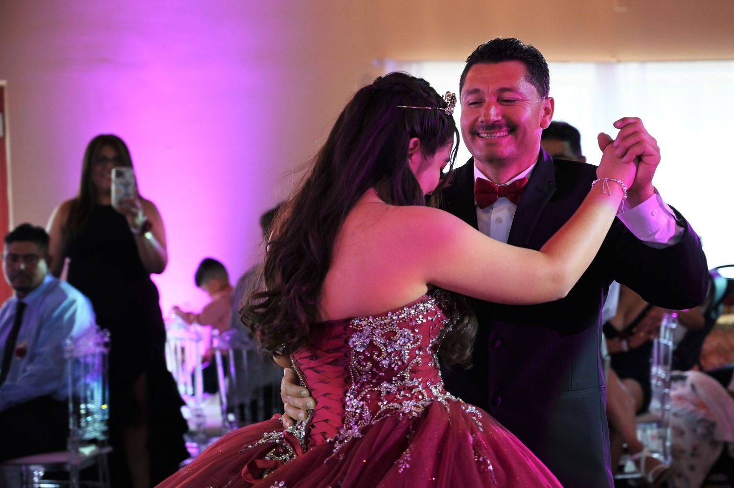 Heartwarming father and daughter dance with the father smiling proudly during the quince celebration.