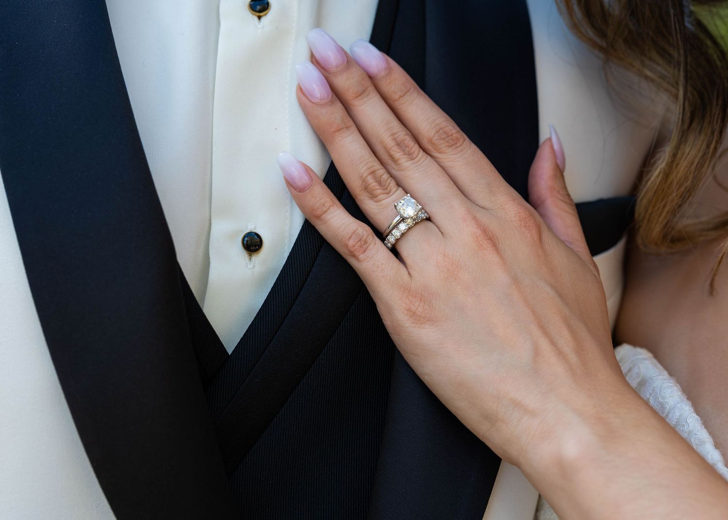 Bride resting her hand on the groom’s chest while showing off her wedding ring.