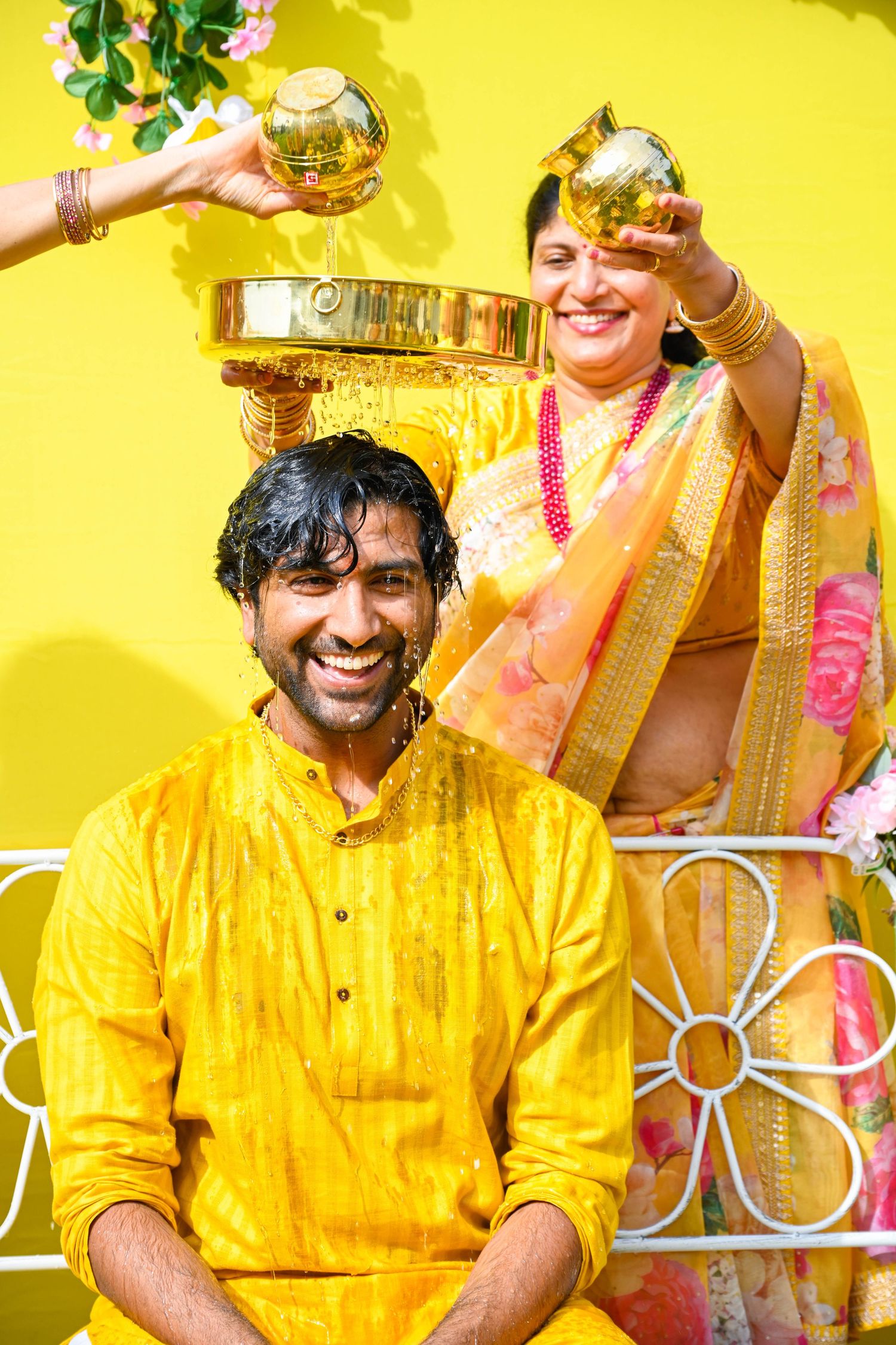 Mother pouring water over her son’s head during a heartfelt haldi moment.
