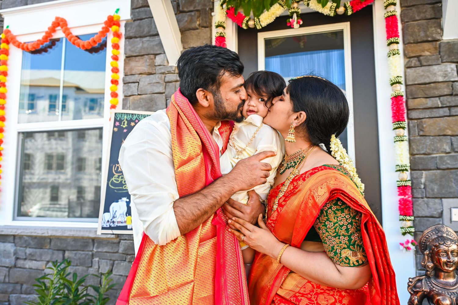 Sweet housewarming moment of the couple kissing their baby boy in front of their new home.