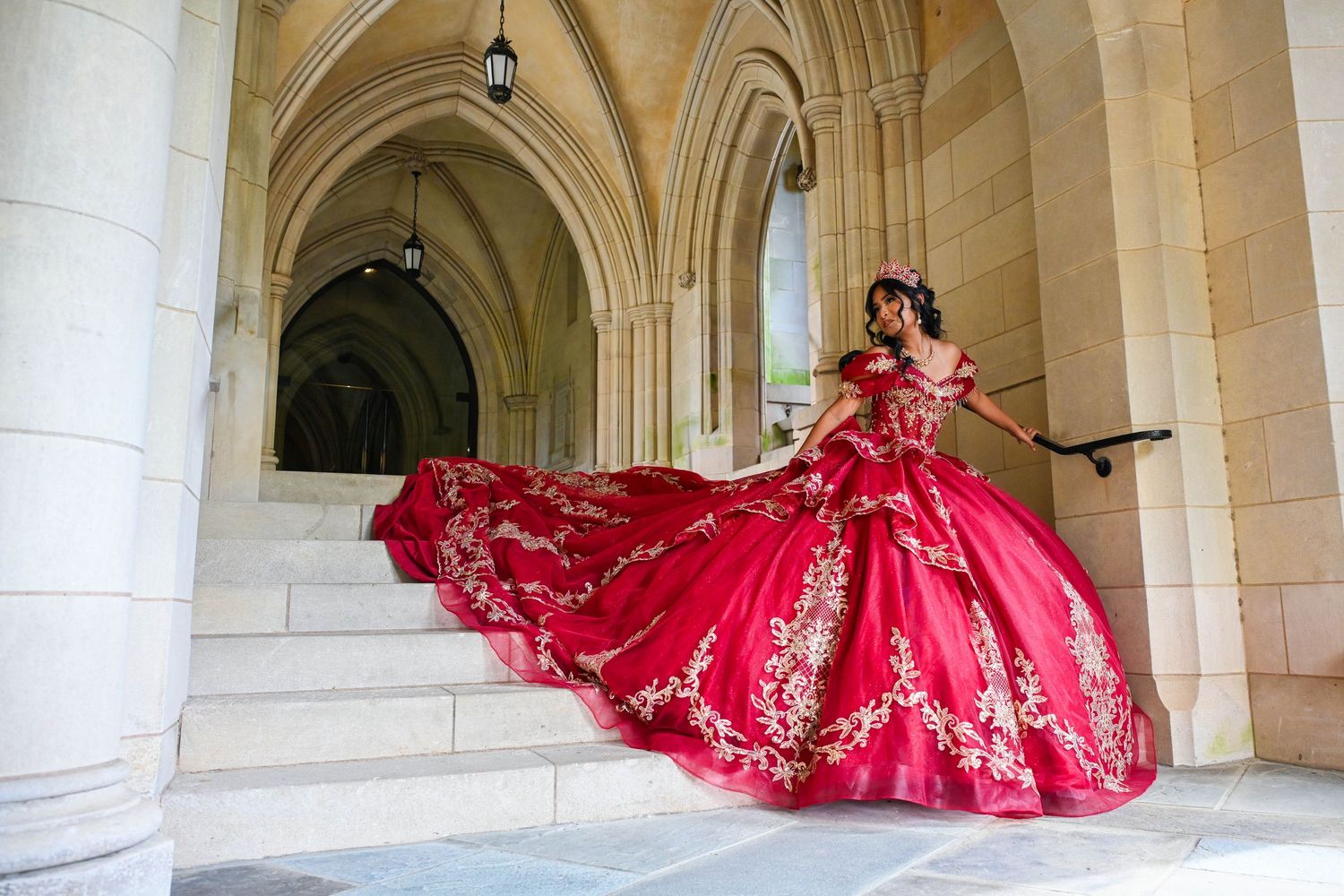 Quinceañera gracefully walking down the cathedral stairs in her stunning red gown.