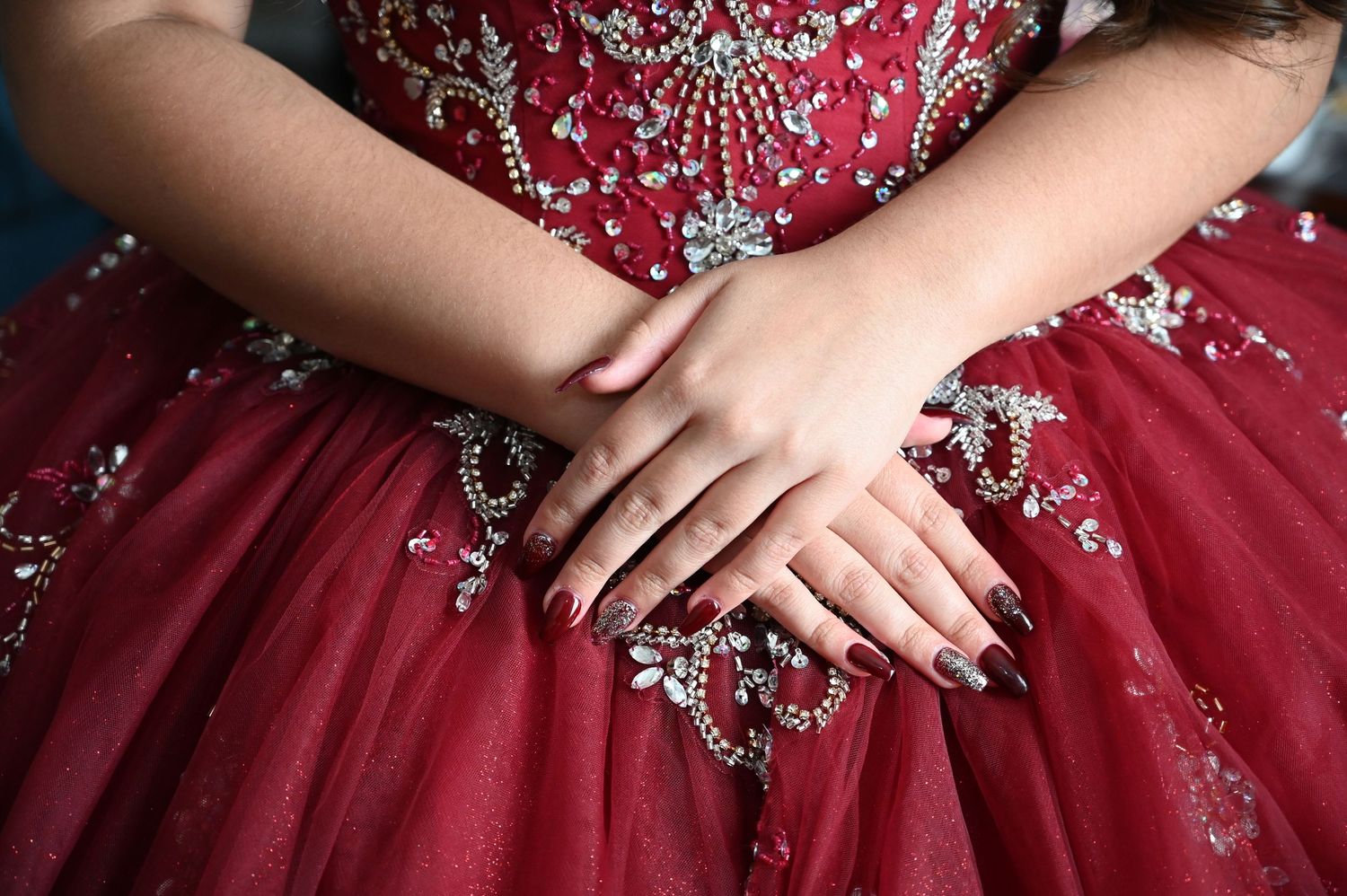 Detailed portrait of the quinceañera placing her hands over her dress to highlight the embroidery and nail art.
