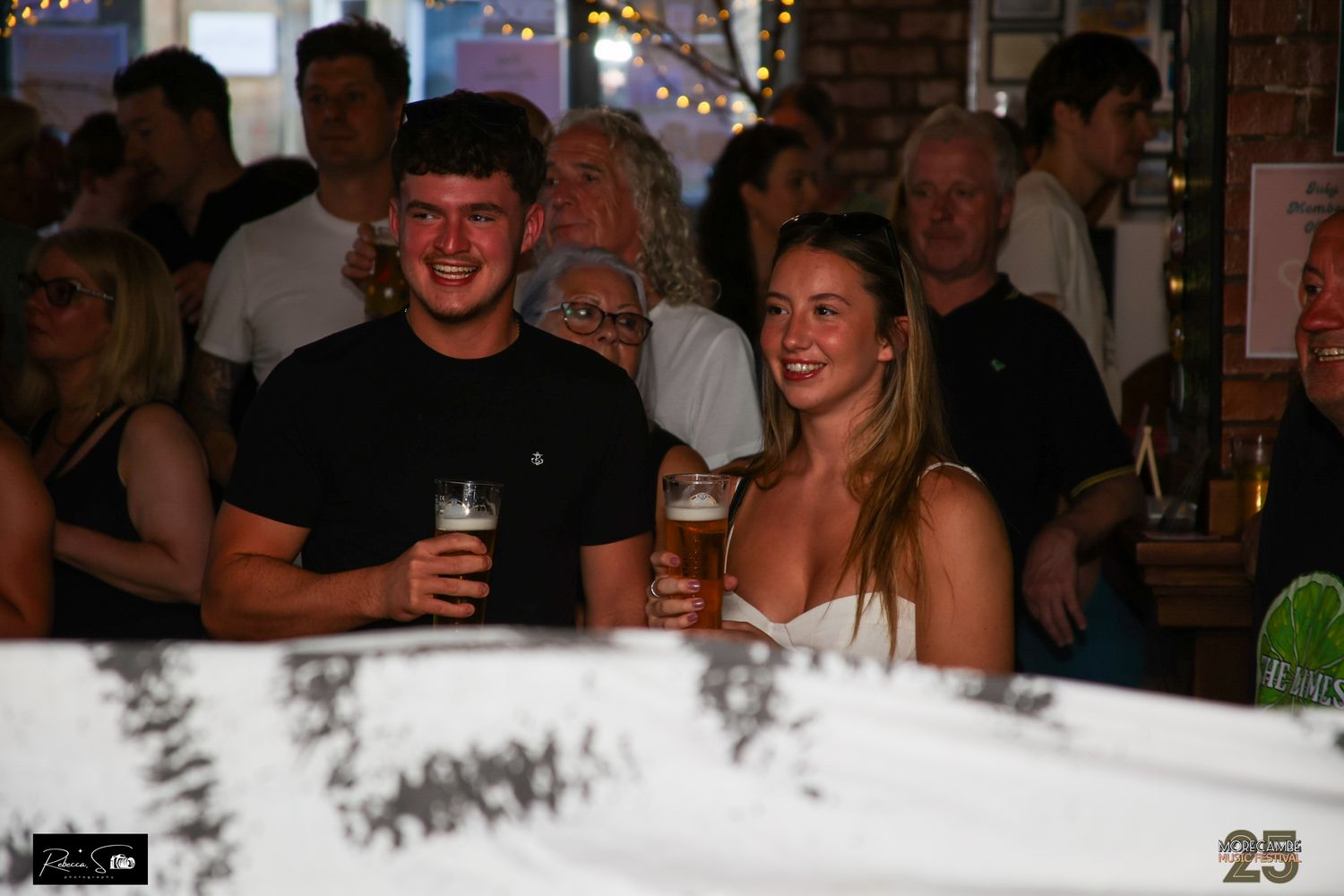 Patrons enjoying drinks and conversation at dimly lit bar interior.