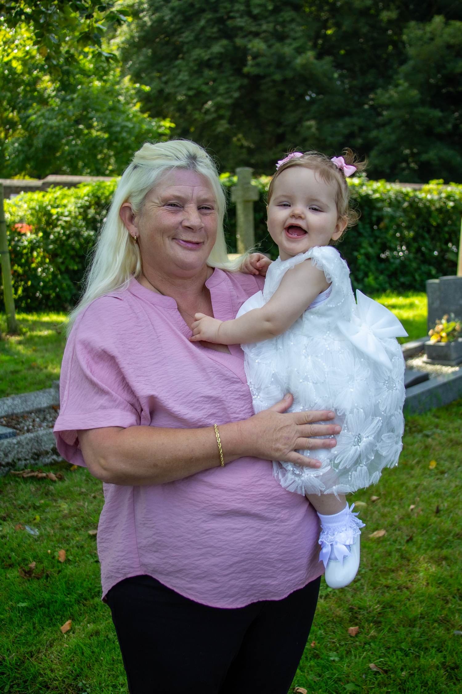 Joyful outdoor photoshoot in a green garden setting with white dress and pink attire.