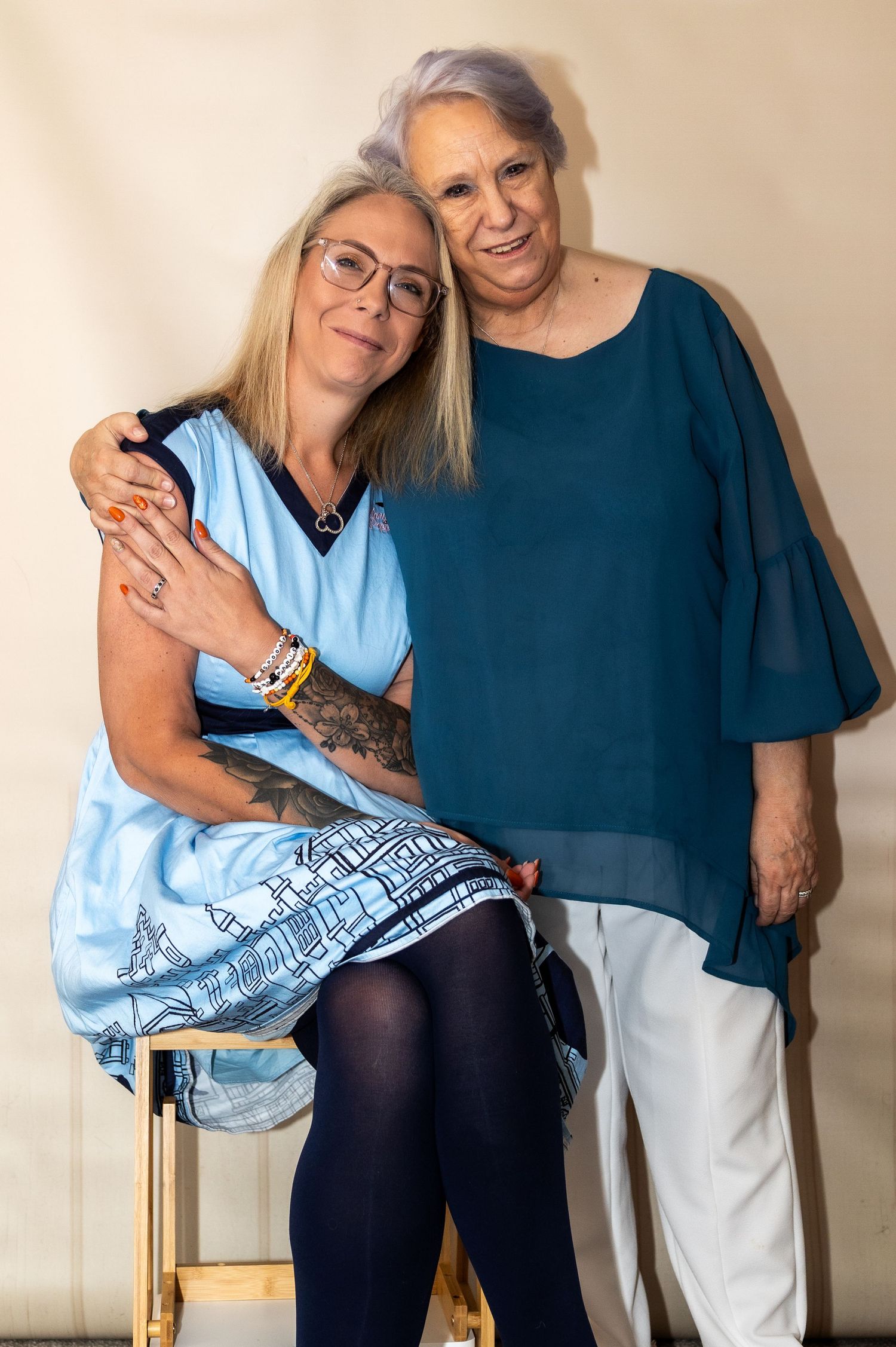 Candid moments captured against beige wall showing emotional connection between two people.