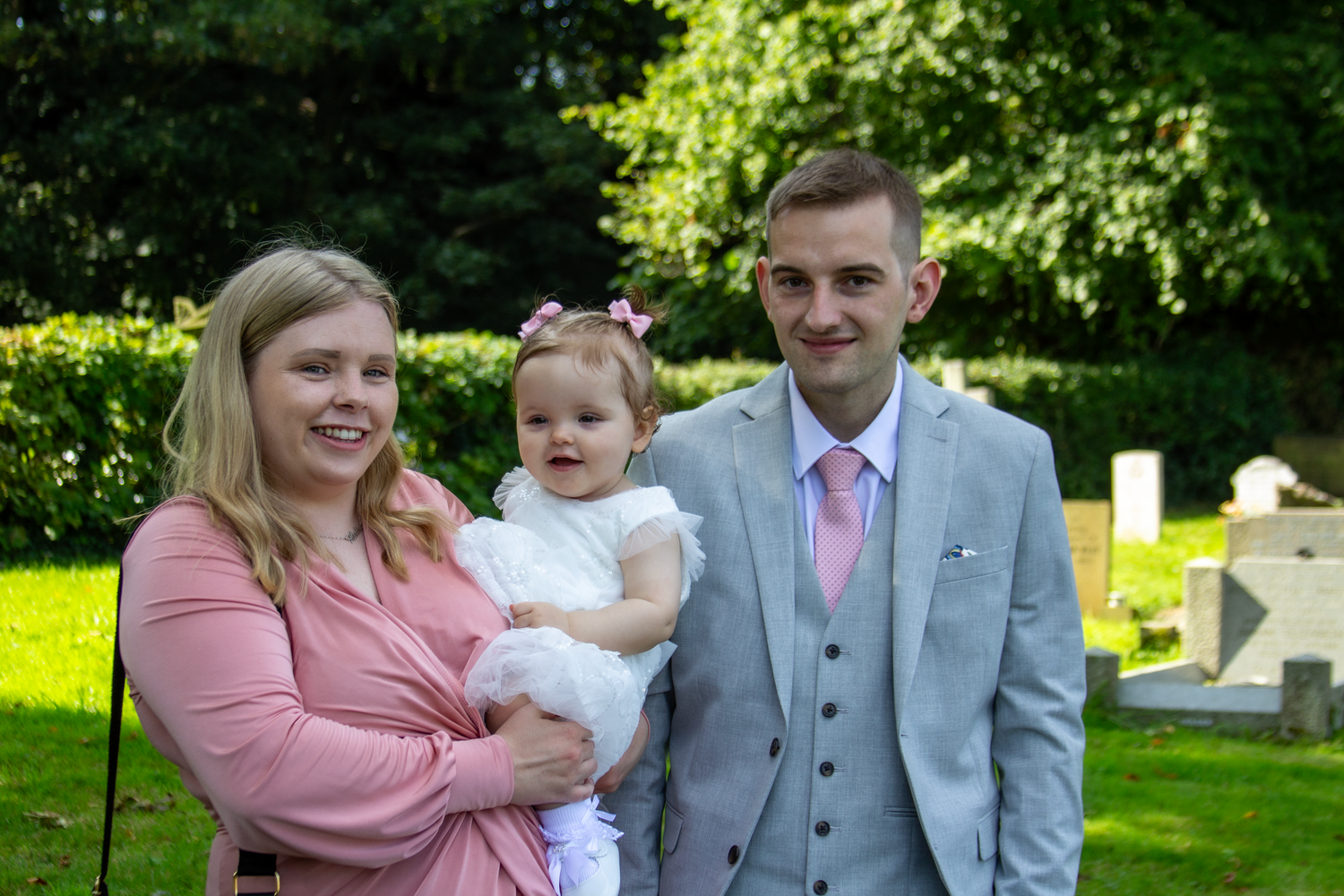 Family photo session in a lush garden setting with pink and grey coordinated outfits.