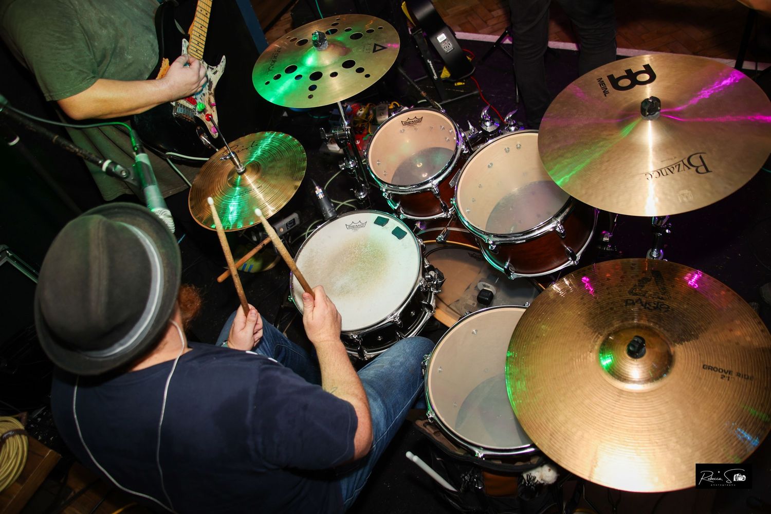 Overhead view of drummer playing illuminated drum kit with cymbals.