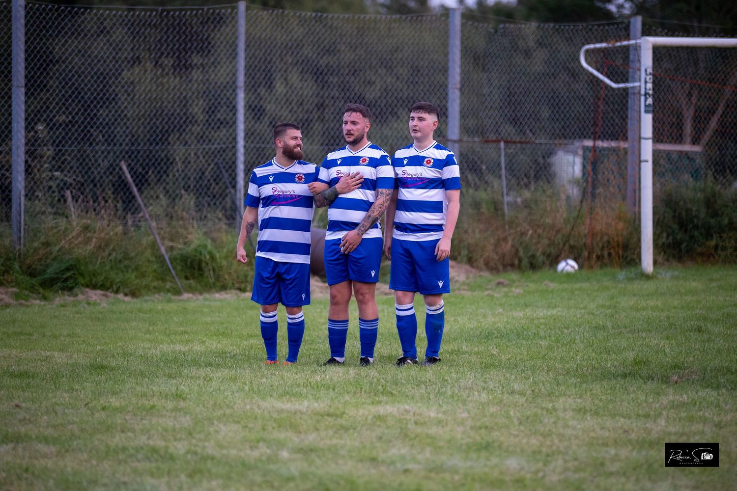 Soccer team in blue and white striped uniforms lined up on a grass field.