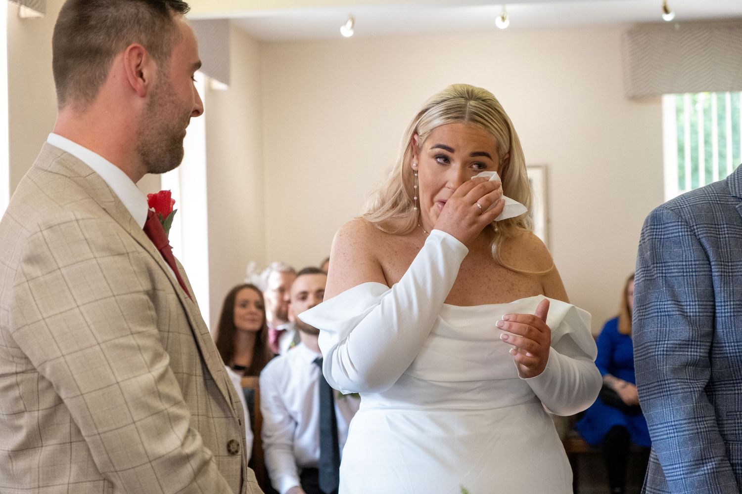 Wedding reception scene with guests in formal attire mingling indoors.