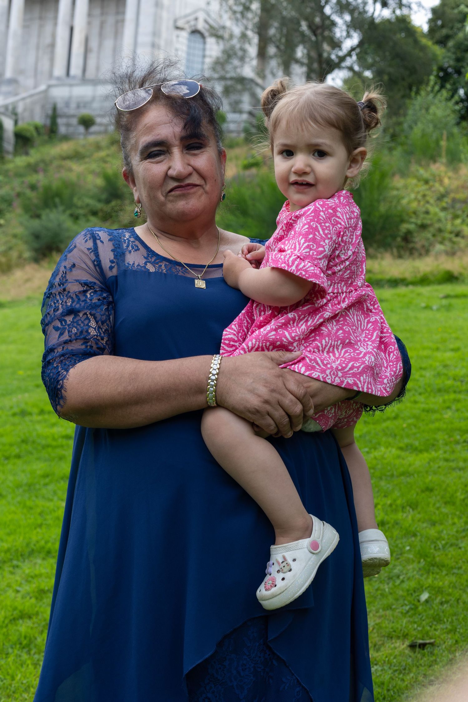 Sweet interactions between family members on a grassy lawn with building in background.