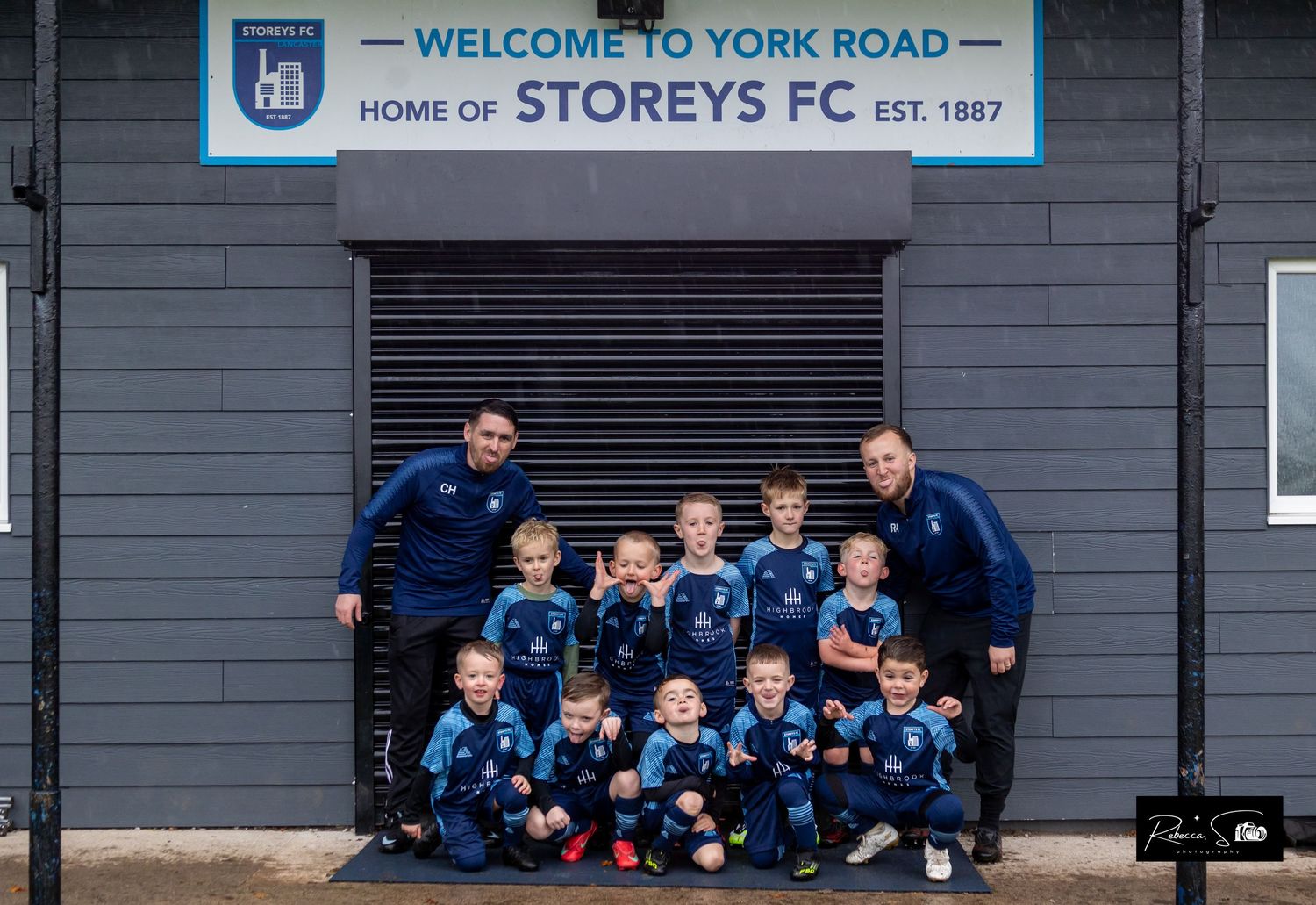 Welcome to York Road sign at Storeys FC stadium with youth team lined up below.