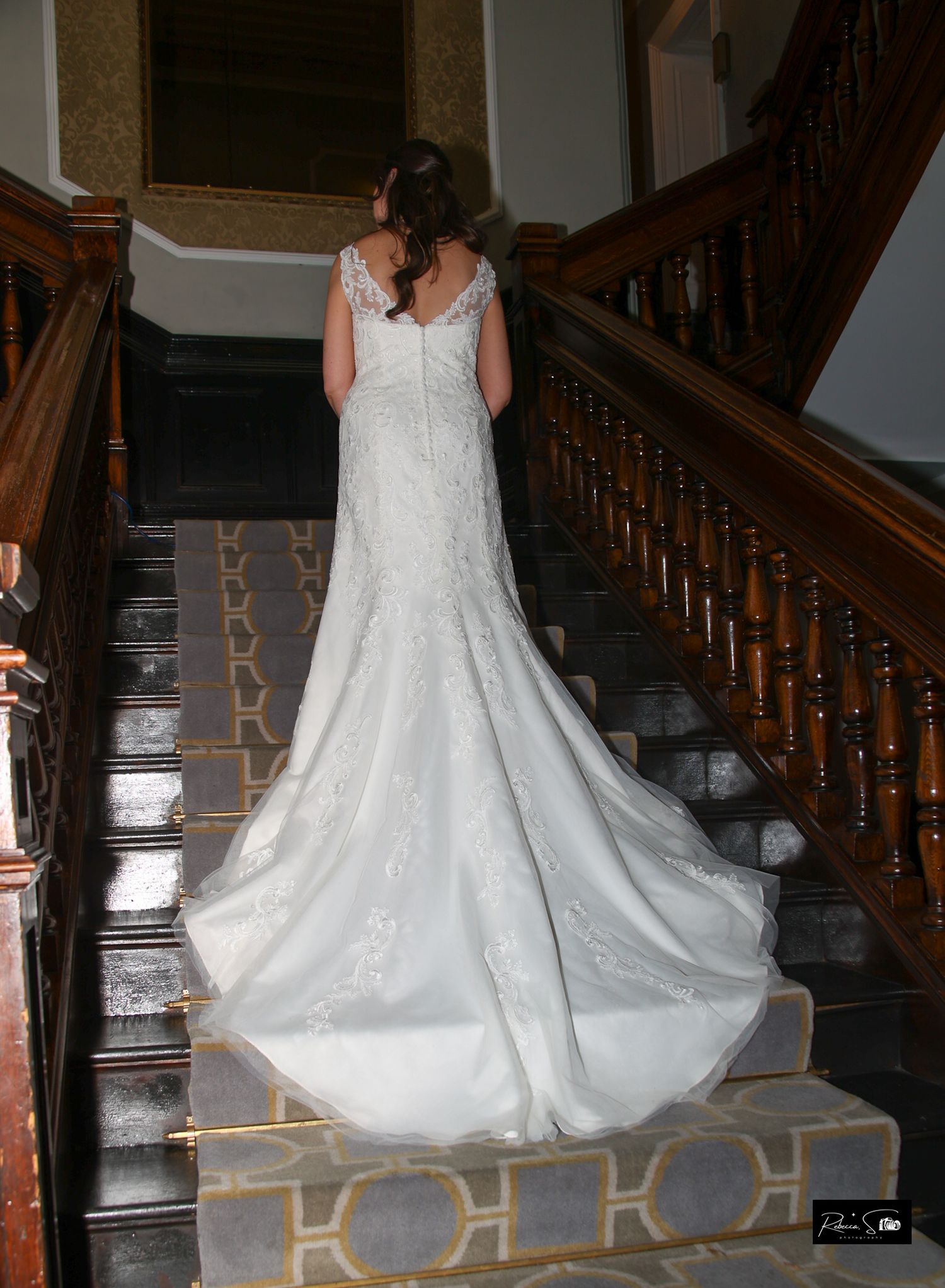 Back view of wedding dress with long train on vintage staircase.