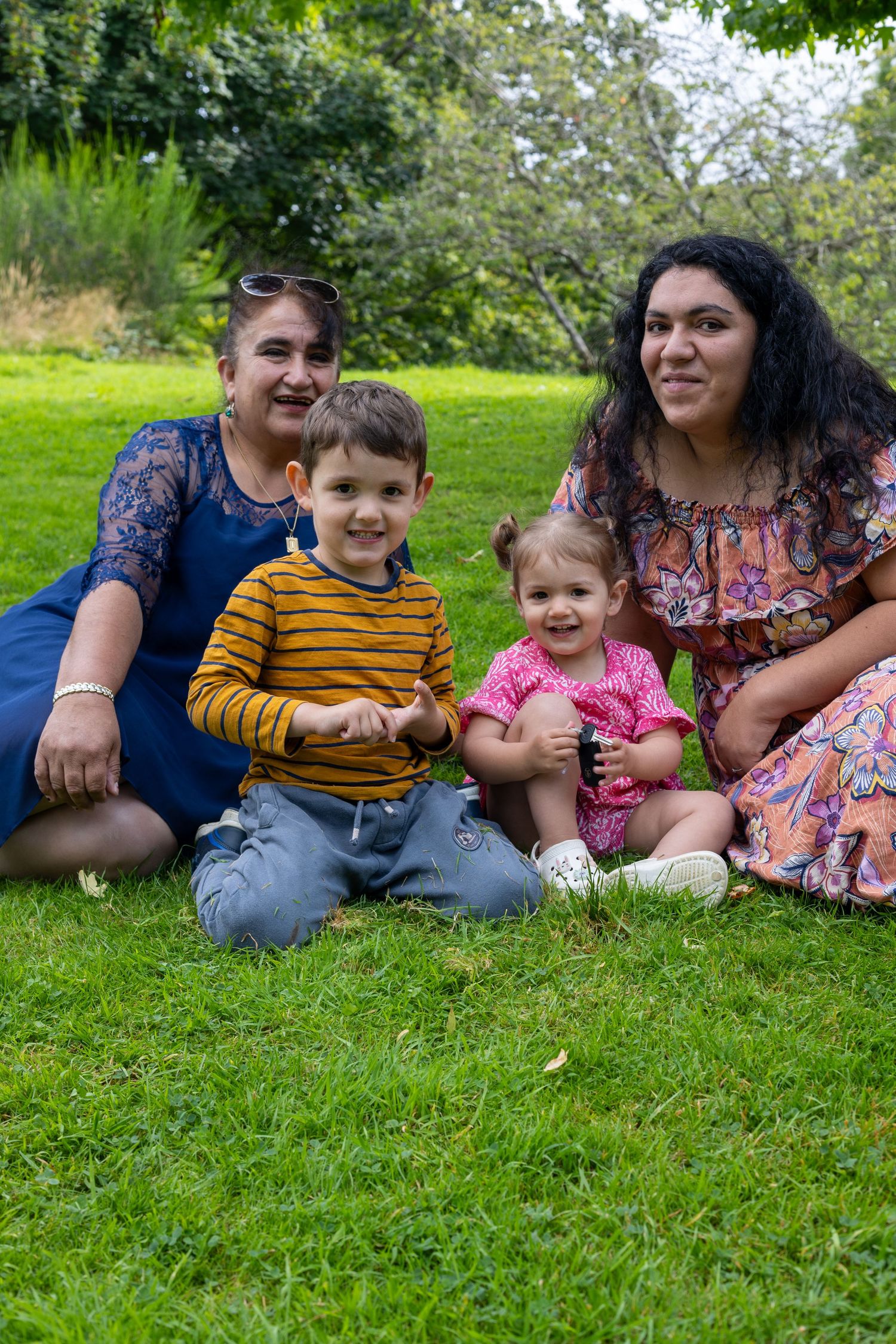 Family members sitting together on green grass during an outdoor photo session.