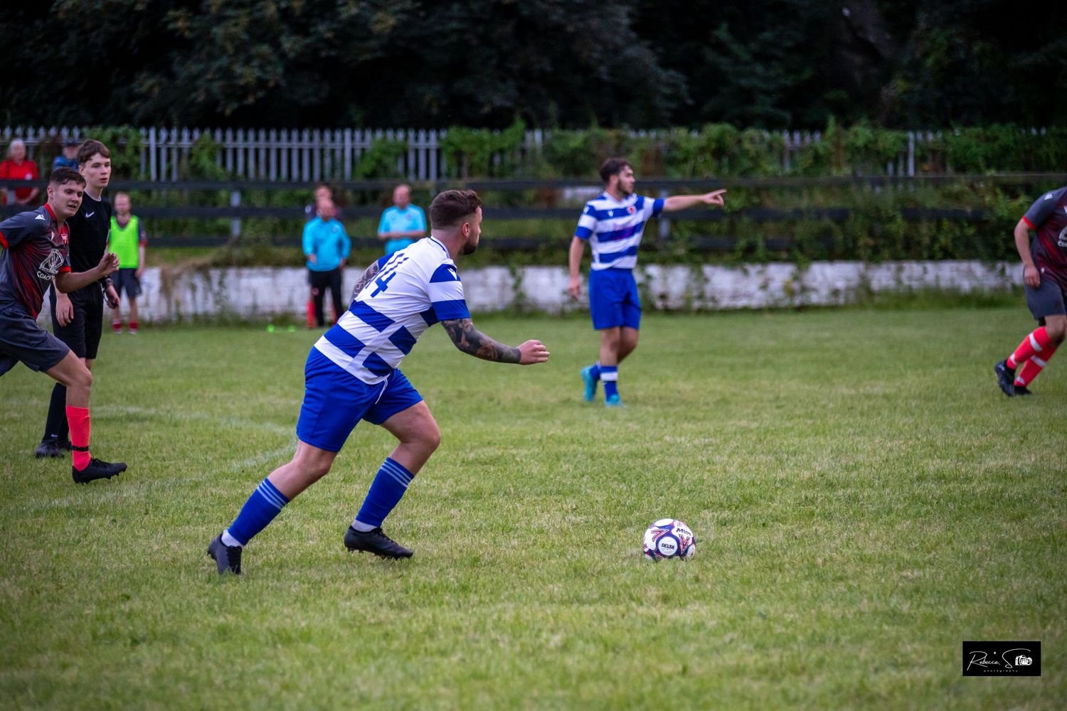 Soccer players chase after the ball during an intense match on a sunny day.