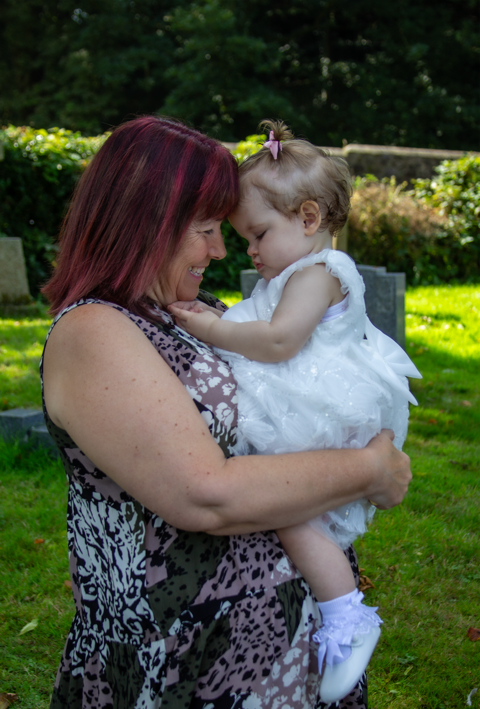 A tender moment captured between two people embracing on a sunny day in a lush green garden setting.