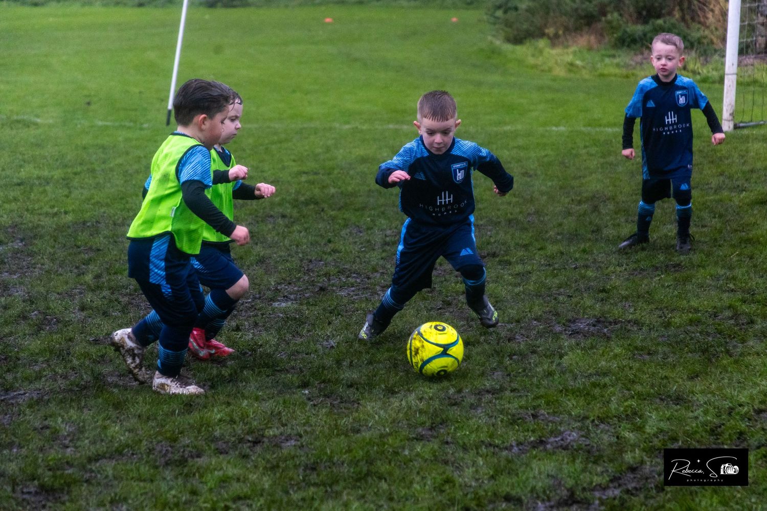 Young players participate in soccer training with yellow balls on grass field.