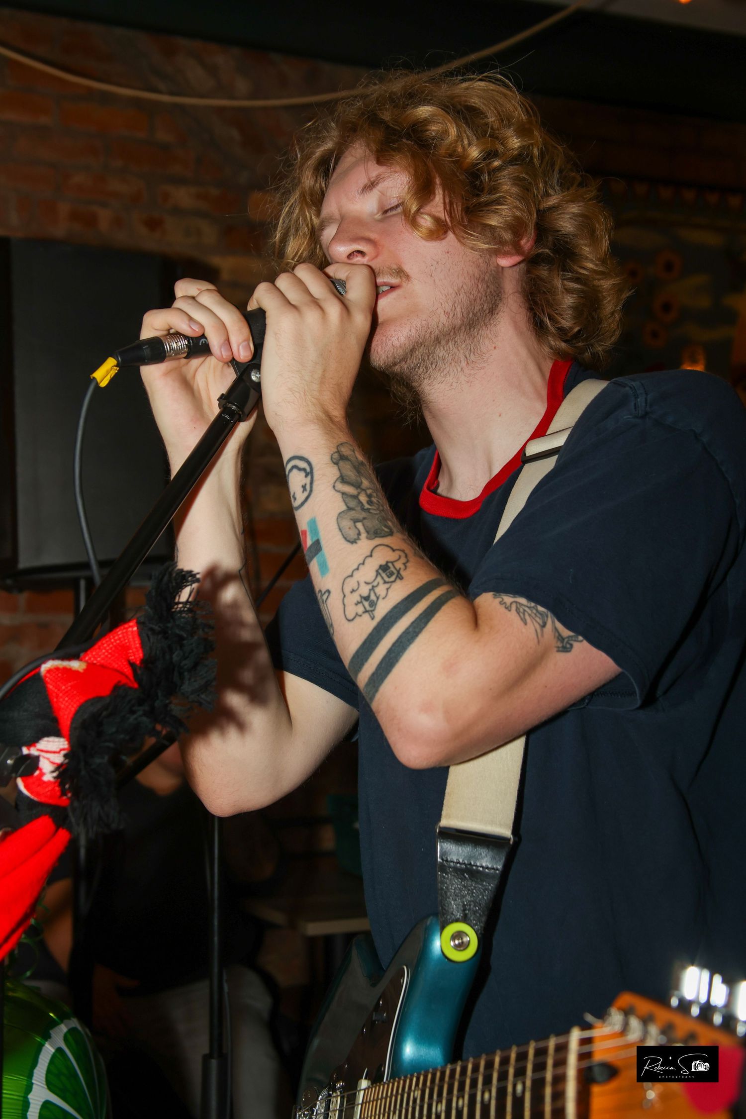 Performer with tattoos sings passionately into a microphone during a live show.