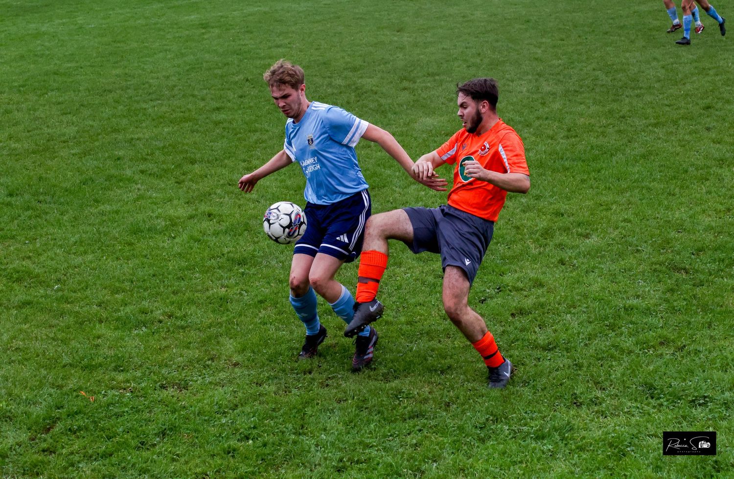 Soccer players compete for ball possession during match on green field.