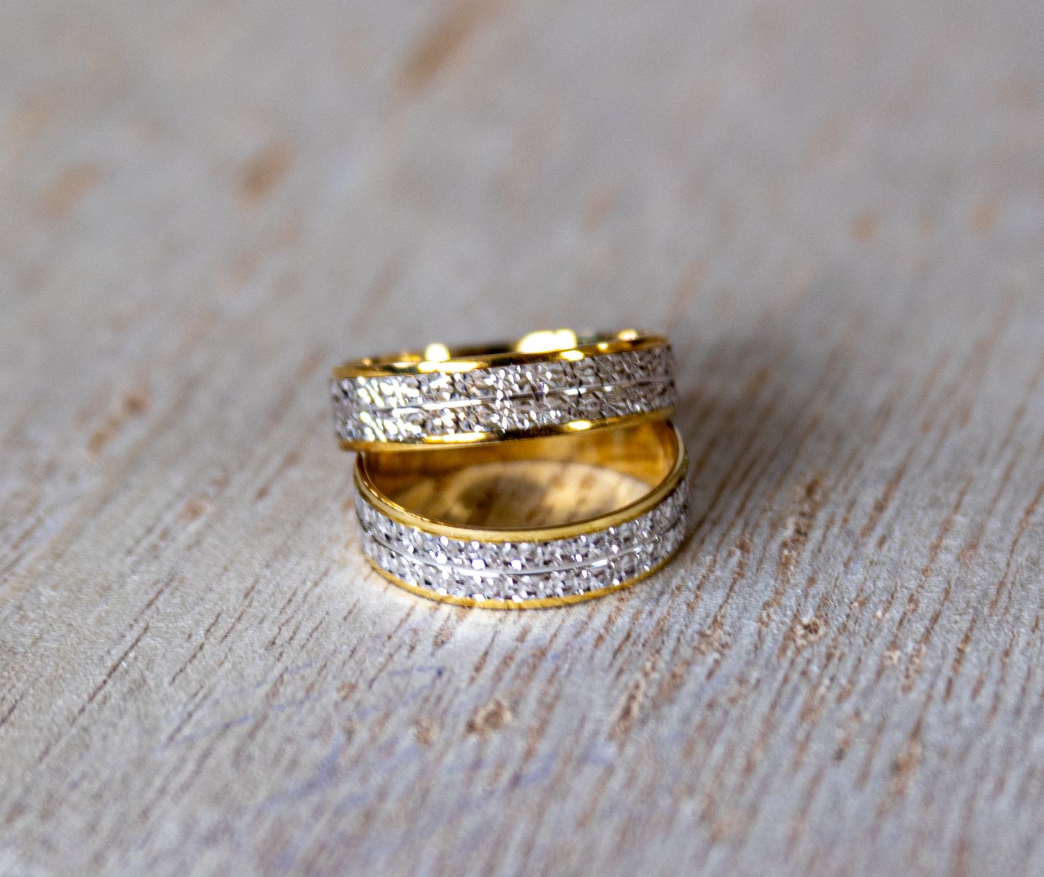 Collection of diamond wedding rings and bands displayed on a rustic wooden surface.