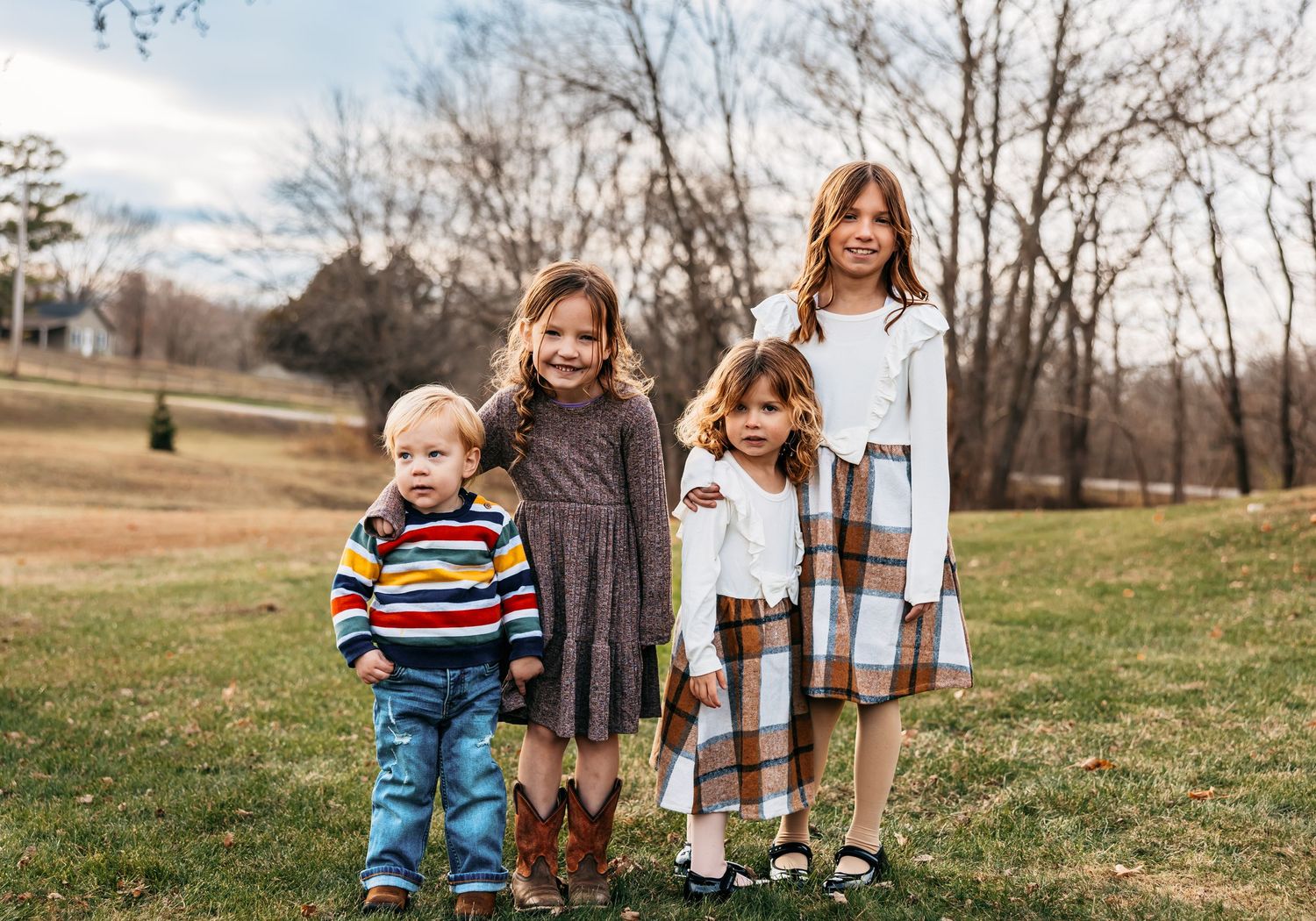 Group photo of children lined up outdoors wearing casual clothing in autumn setting.
